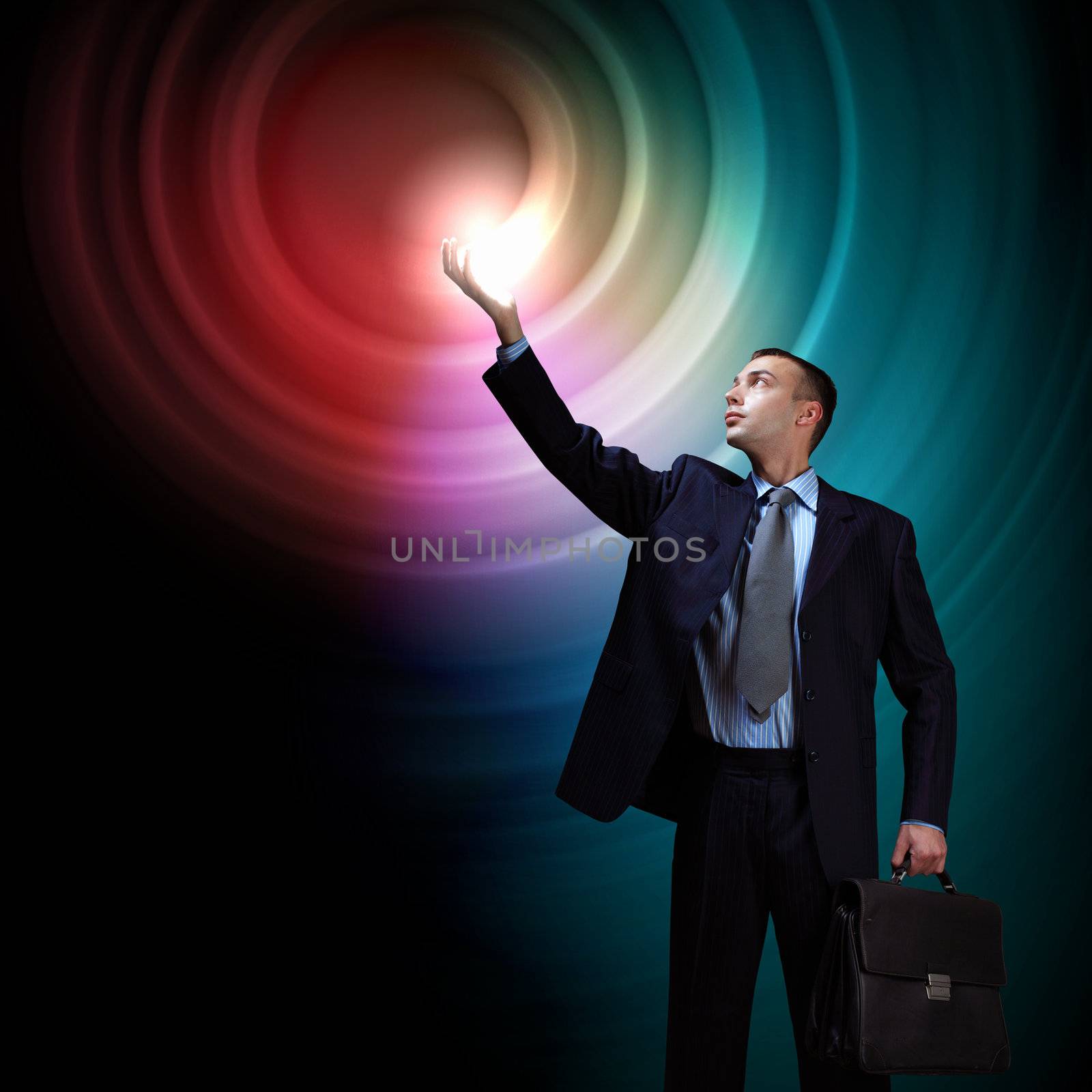 Young successful businessman holding a shining light in his hand as a symbol of success and advancement.