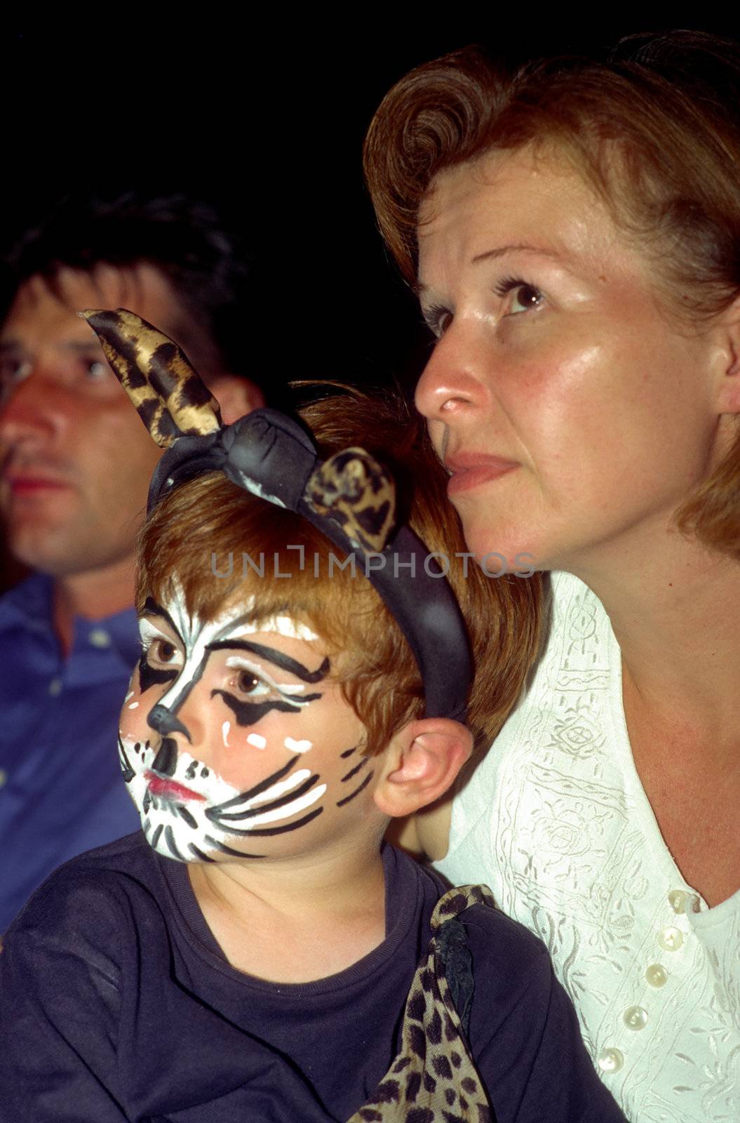 boy and mother are watching a performance, boy has a cat makeup  by meinzahn