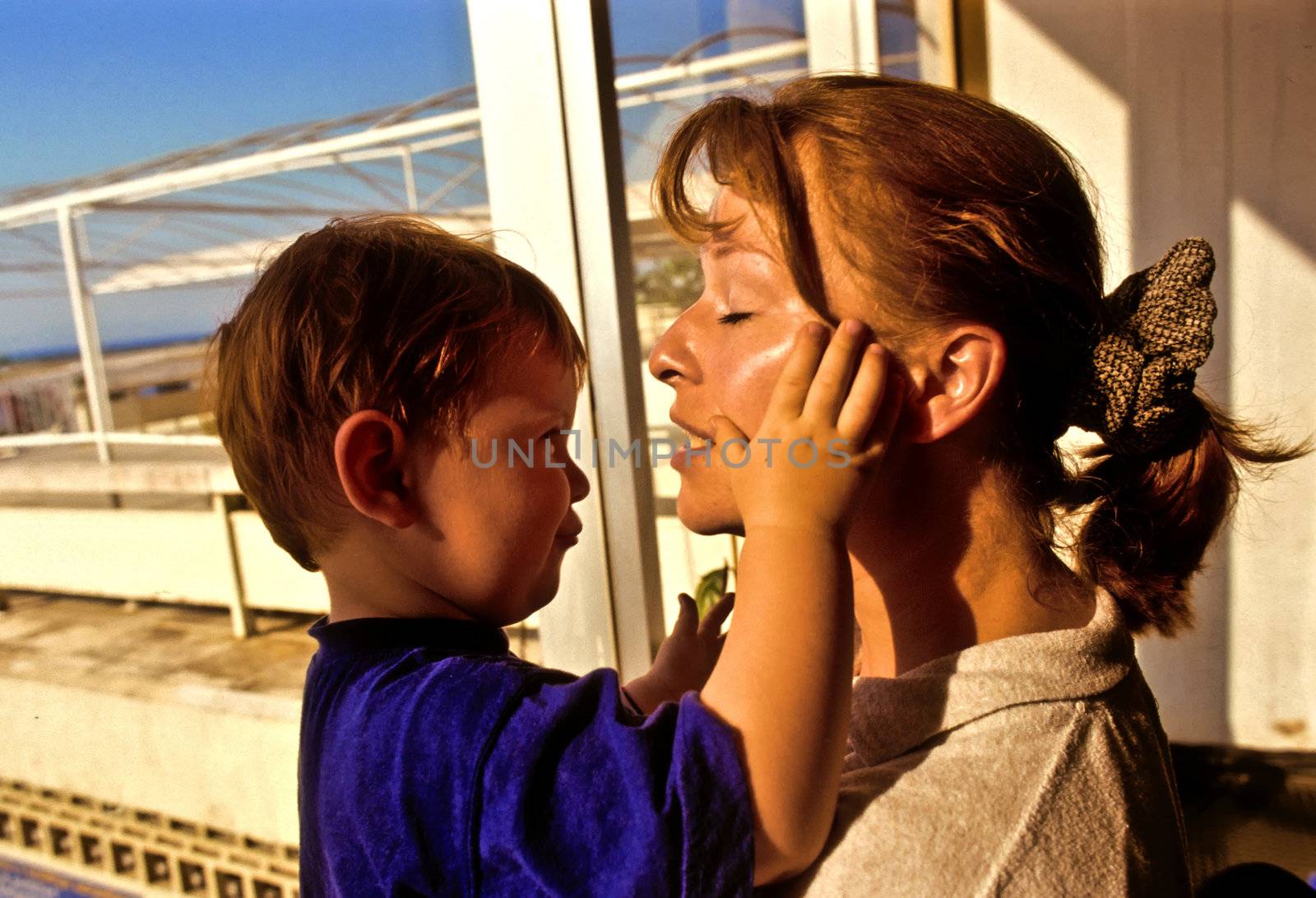 young boy is hugging his mother in the sun