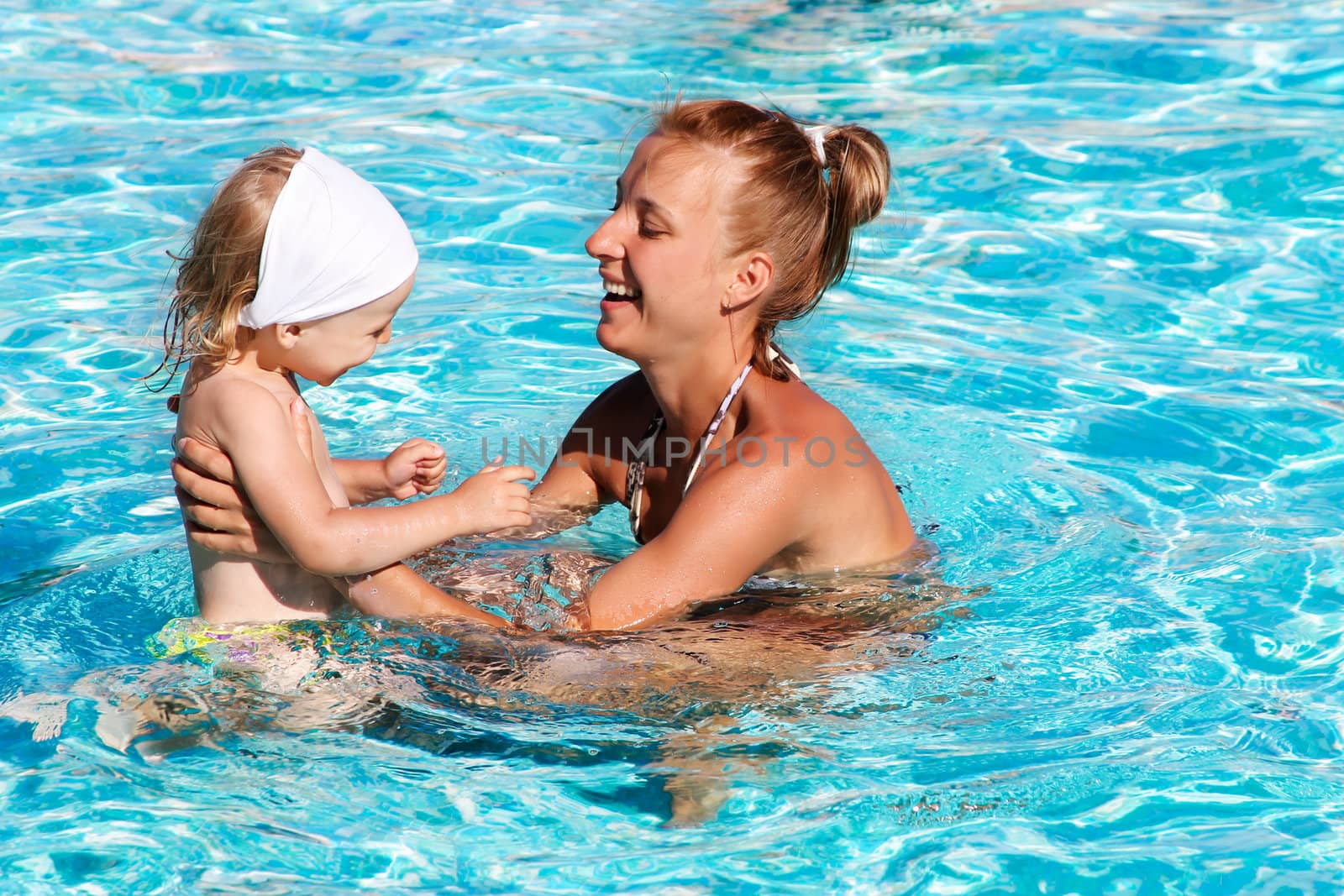 Happy kid playing with mother in swimming pool by Angel_a