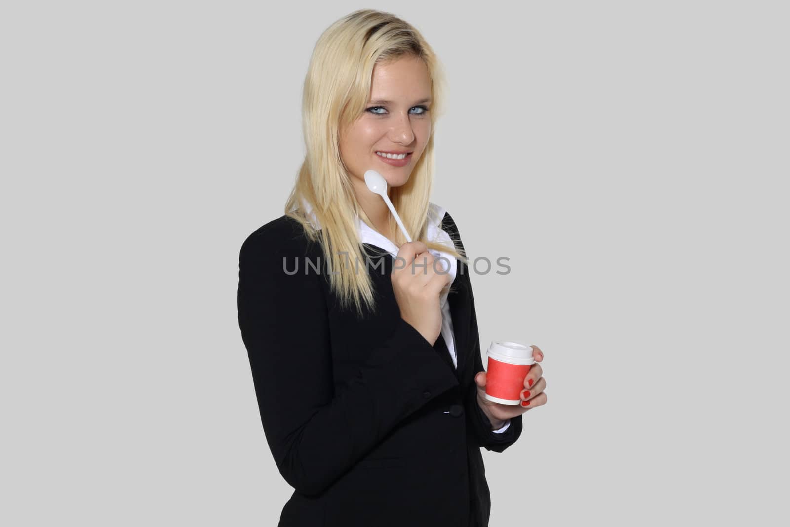 Happy secretary woman with coffee, teaspoon and cup in a gray background