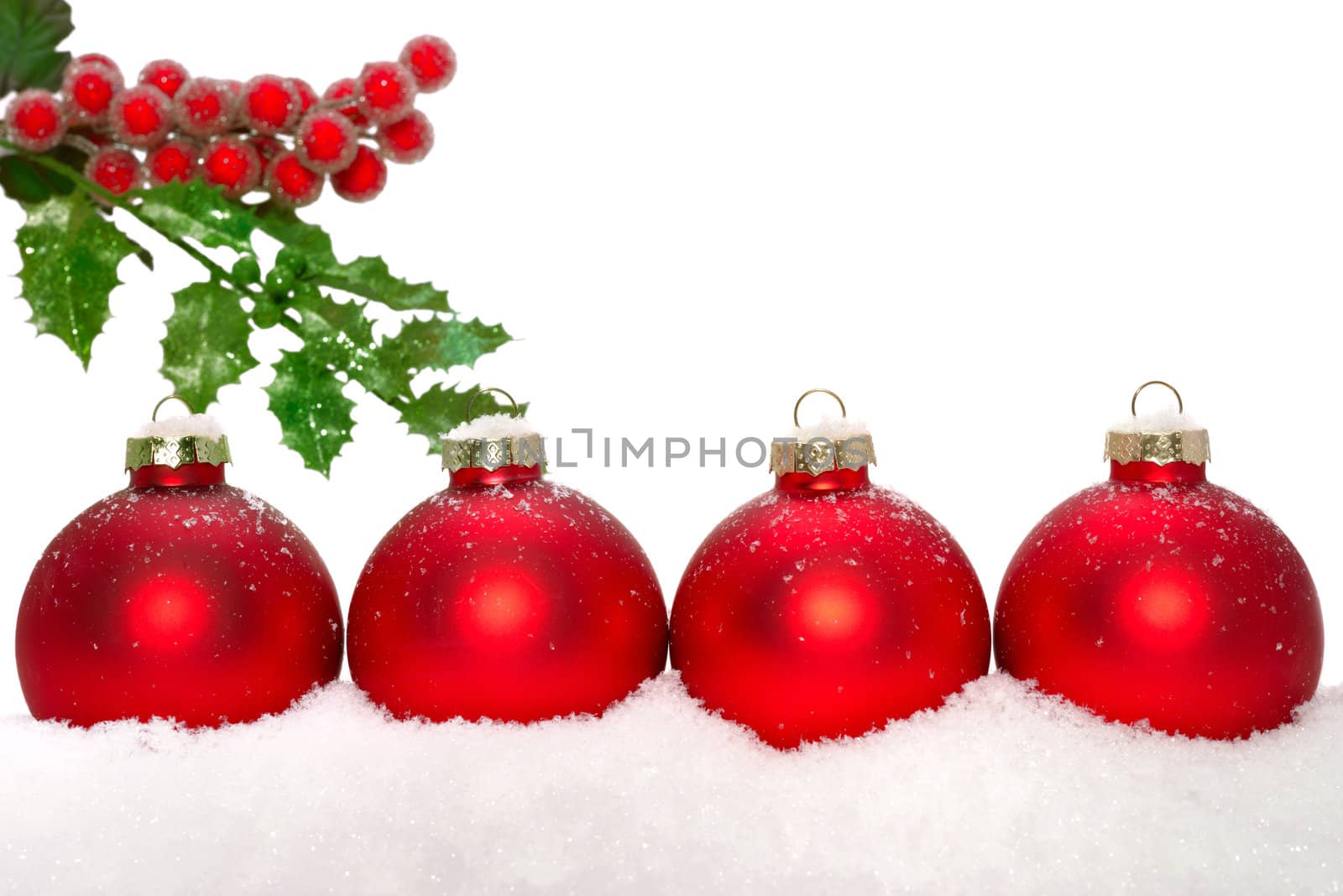 Close up of decorative Christmas ornaments on the snow, and holly.