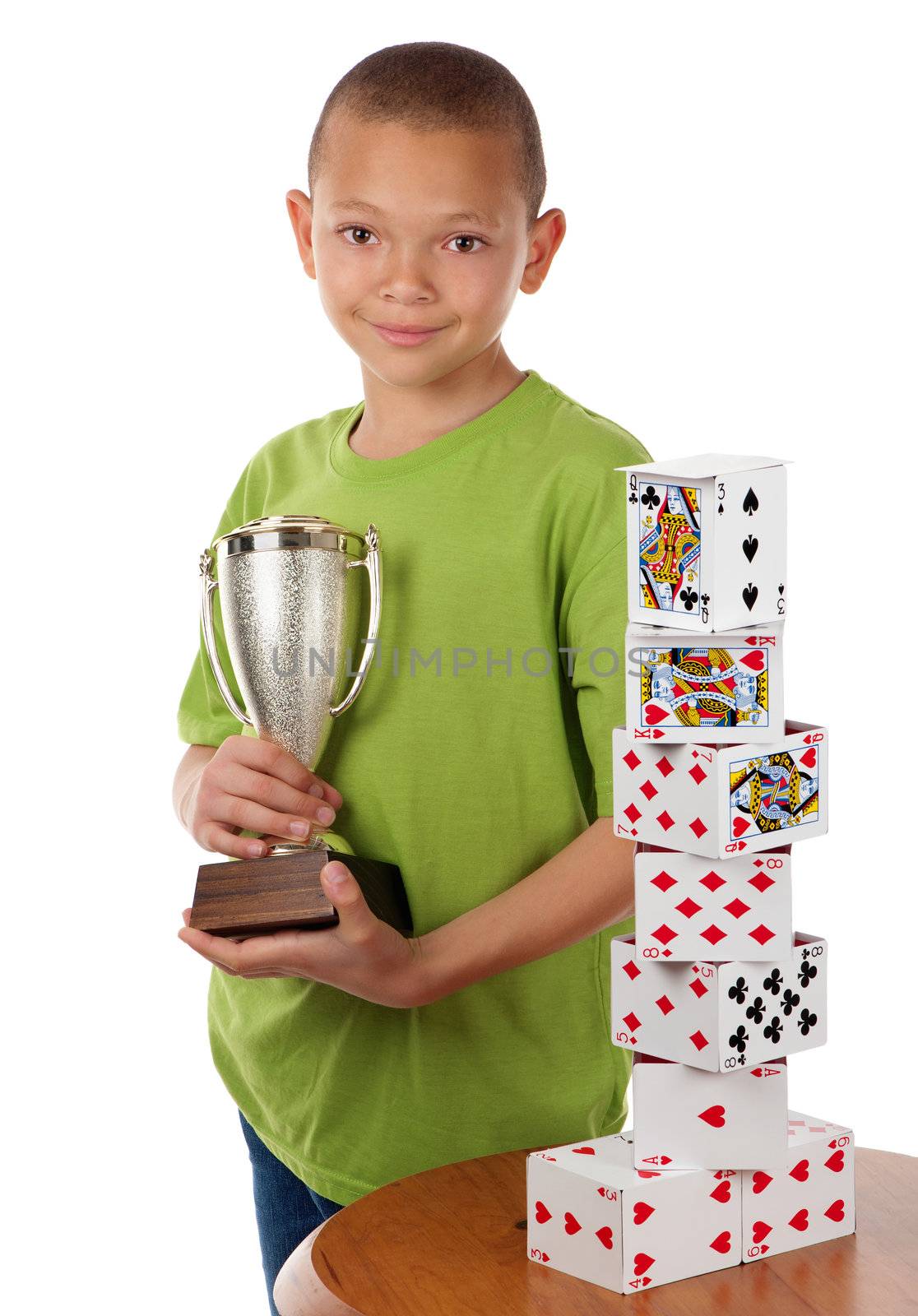 A young boy proudly holds the winning trophy in a playing card building competition.