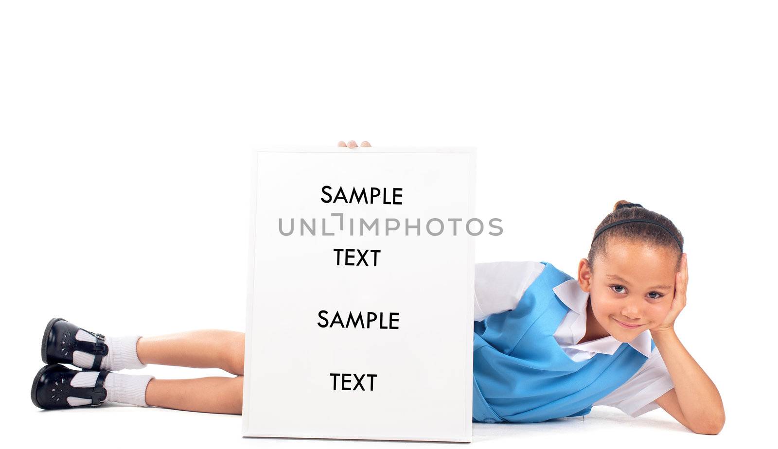 A cheerful little girl lies on the floor showing a "back to school" poster.