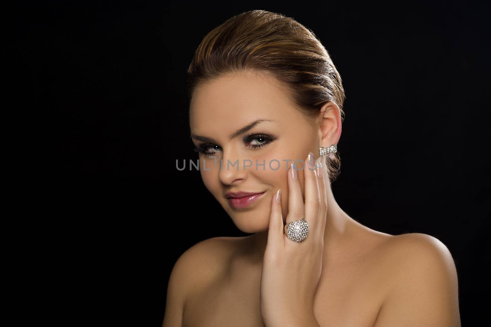 Beautiful glamorous woman with naked shoulders and a lovely smile, head and shoulders portrait on a dark studio background with copy space