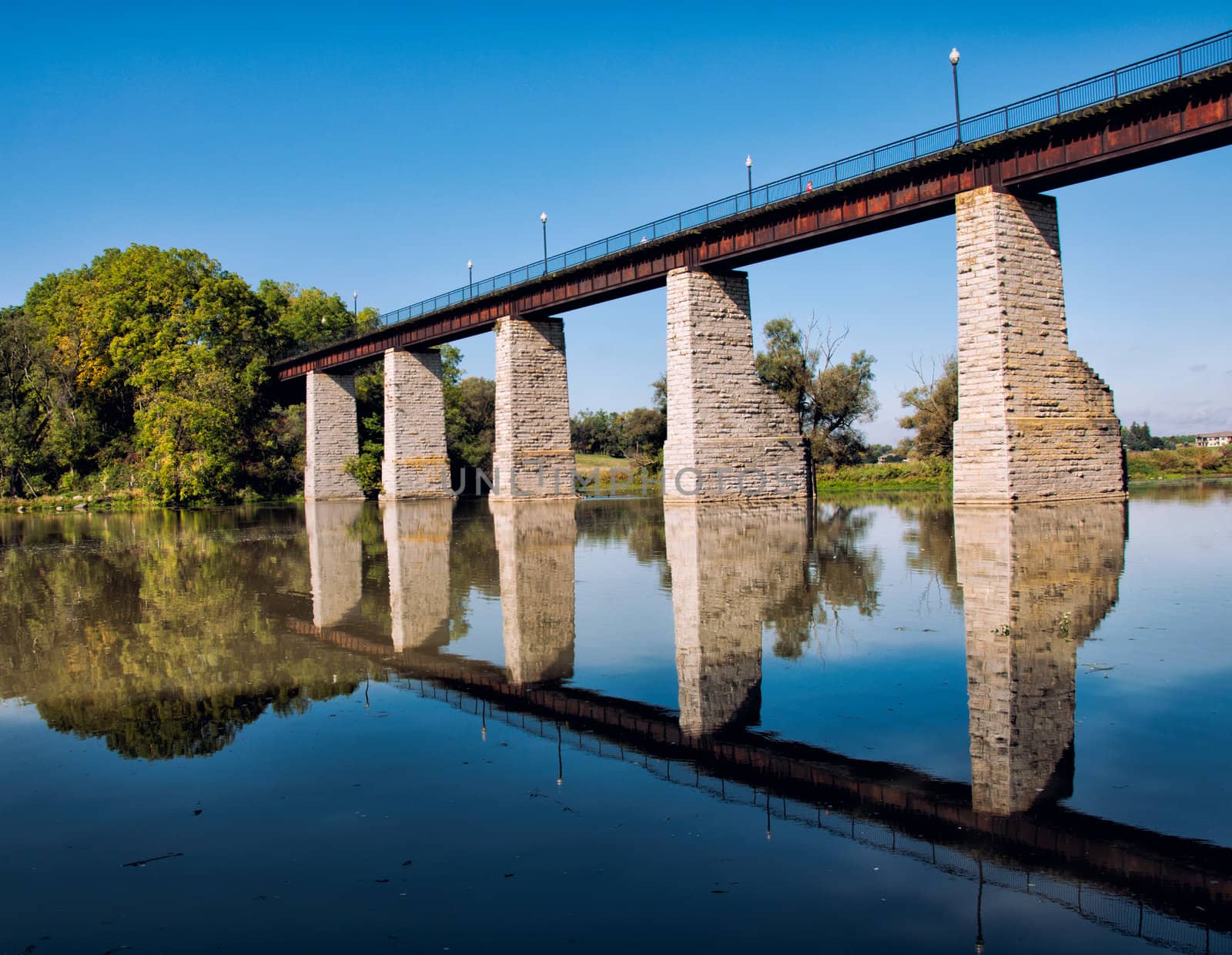 Historic railroad trestle over river with reflection in the river.