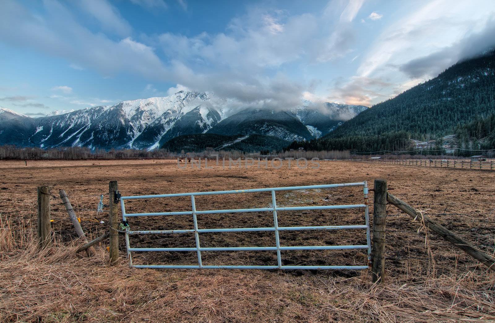 Fence gate for a farm pasture with snowy mountains in background