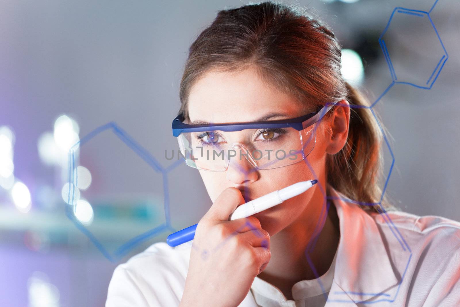 Portrait of a confident female health care professional in his working environment reviewing structural chemical formula written on a glass board.