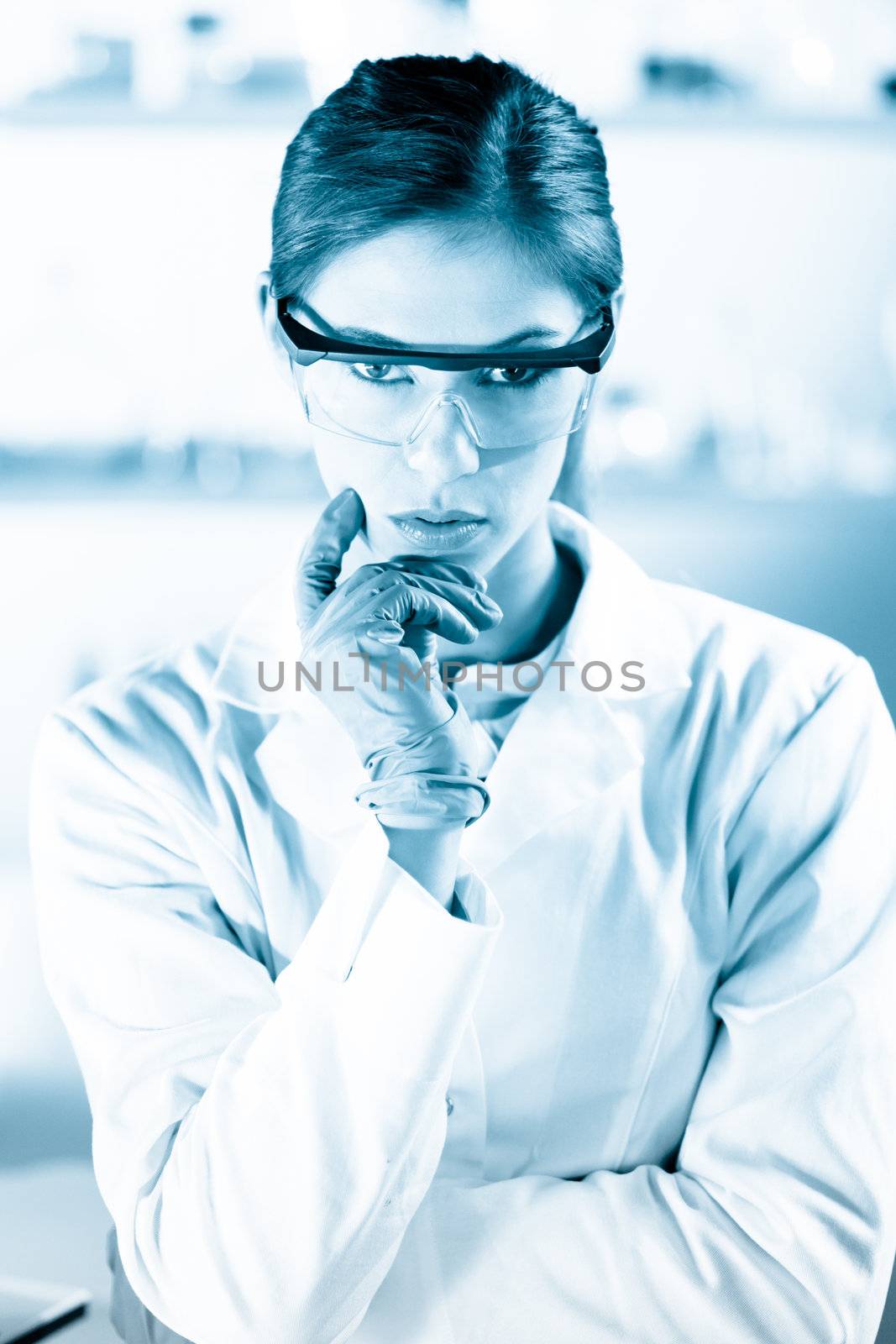 Portrait of an attractive, young, confident female health care professional in his working environment. Black and white, blue toned portrait.