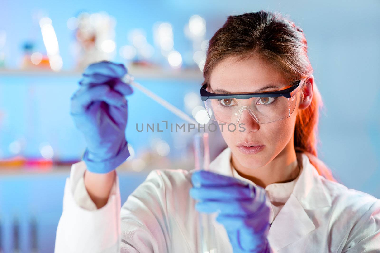 Attractive young scientist pipetting. by kasto