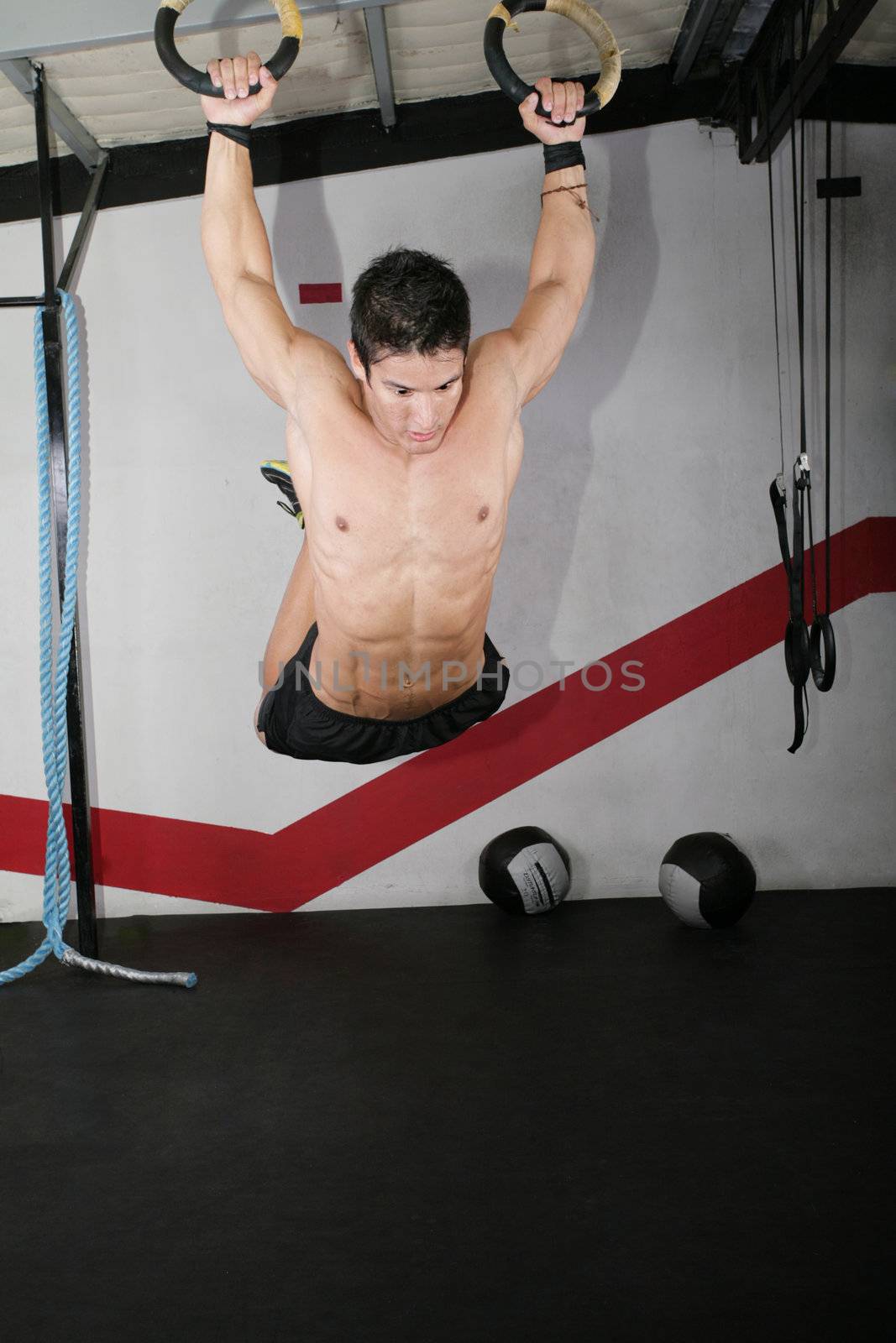 Ring dip crossfit exercise over a dark background.