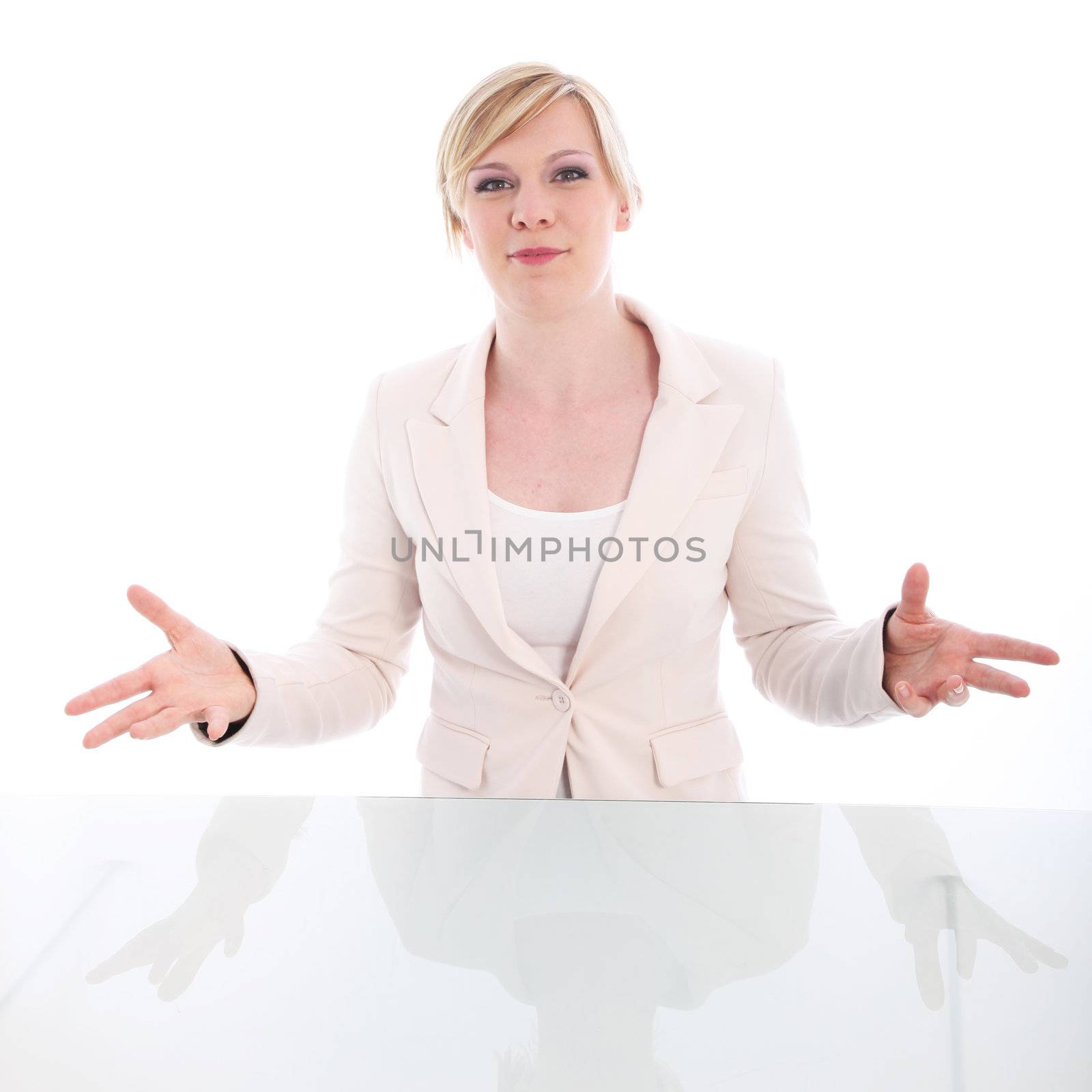 Eloquent young woman standing behind a reflective table pleading her case accompanied with expressive hand gestures on a white studio background