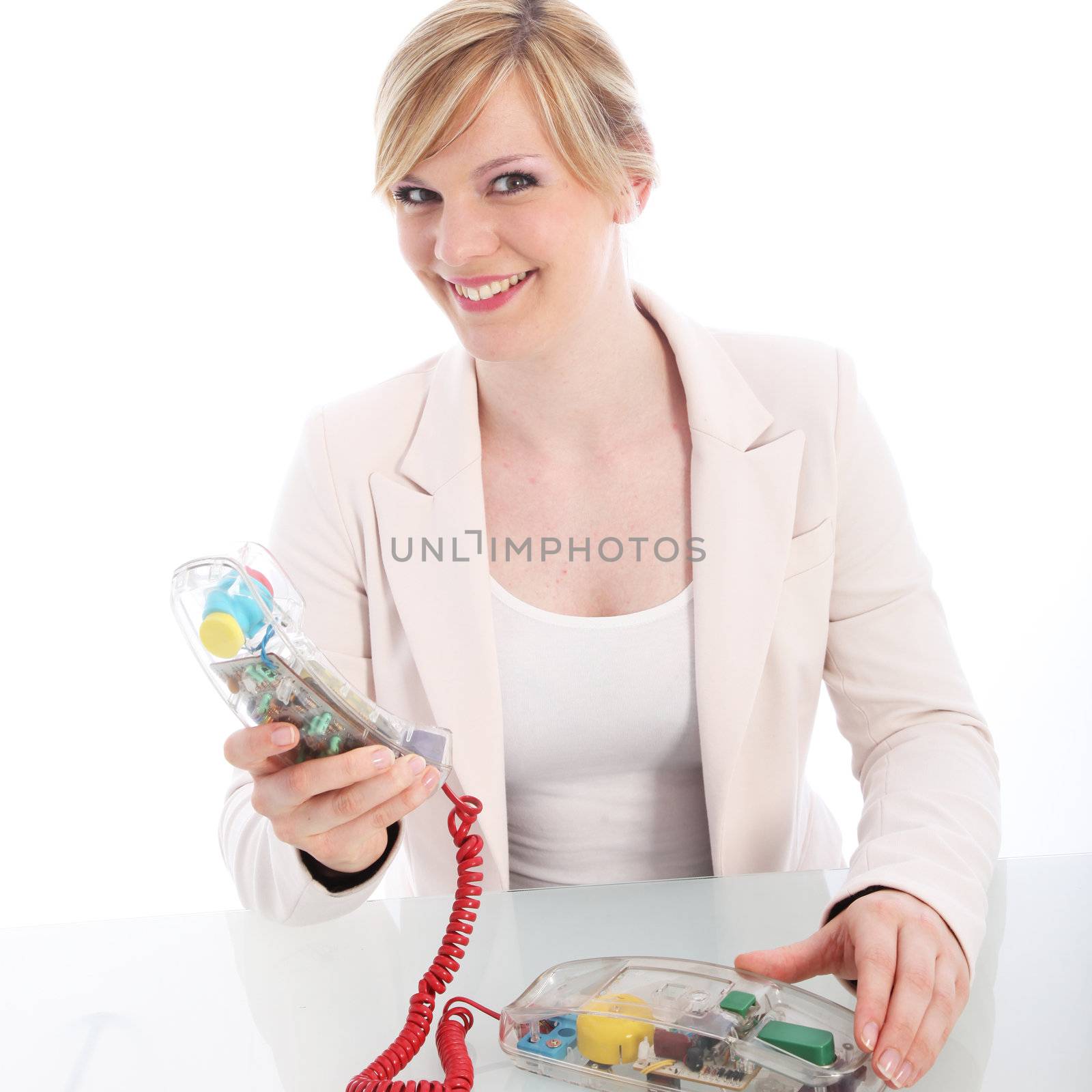Smiling woman using a landline telephone with a bright red cord and modern transparent instrument