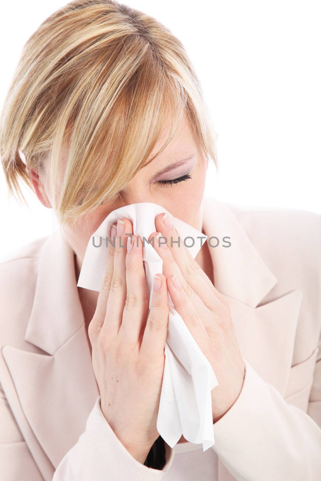 Young blonde woman is suffering from a cold or flu and is sneezing into a tissue. Studio portrait over white