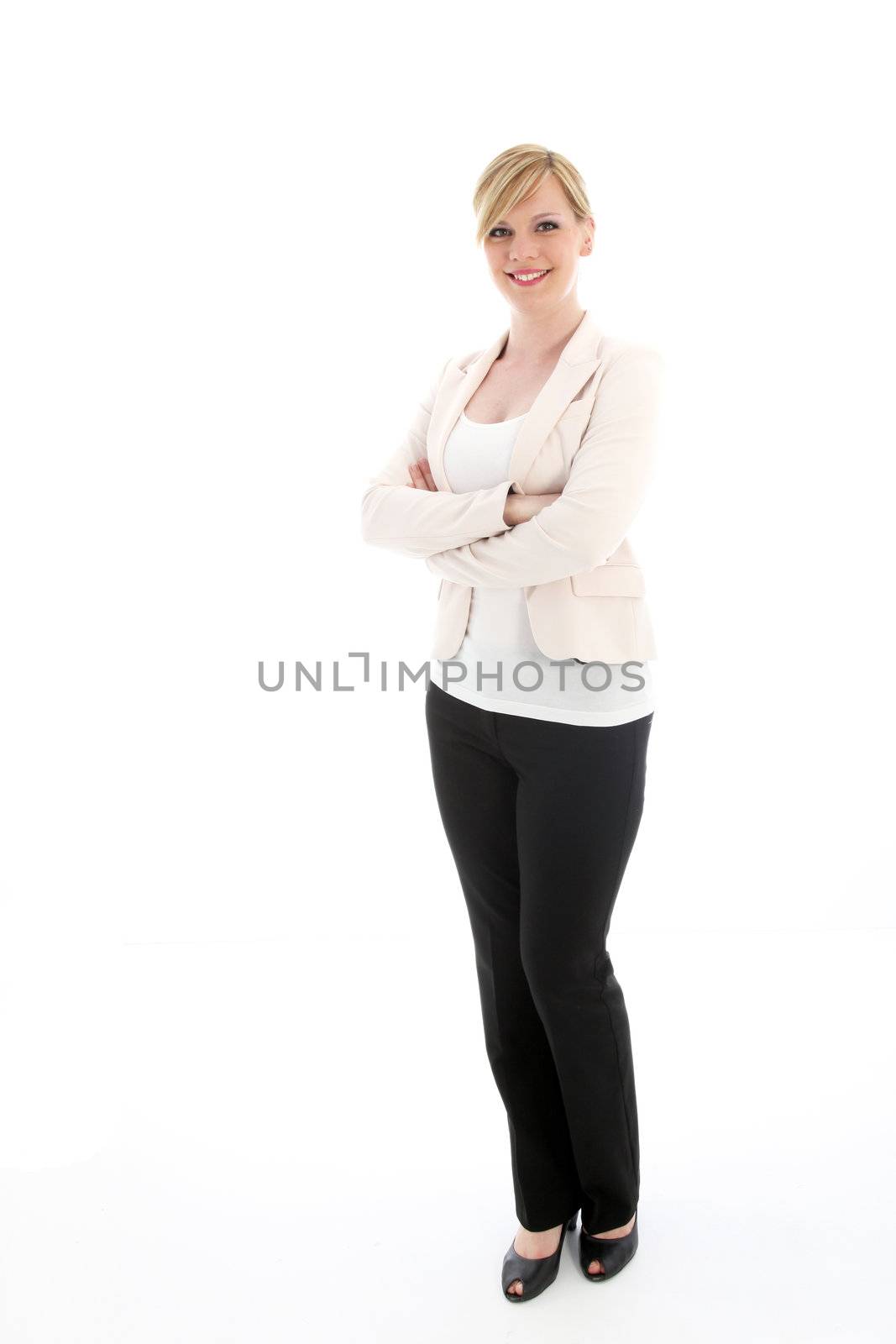 Full length studio portrait of a stylish professional woman in slacks and a jacket standing smiling with her arms crossed isolated on white