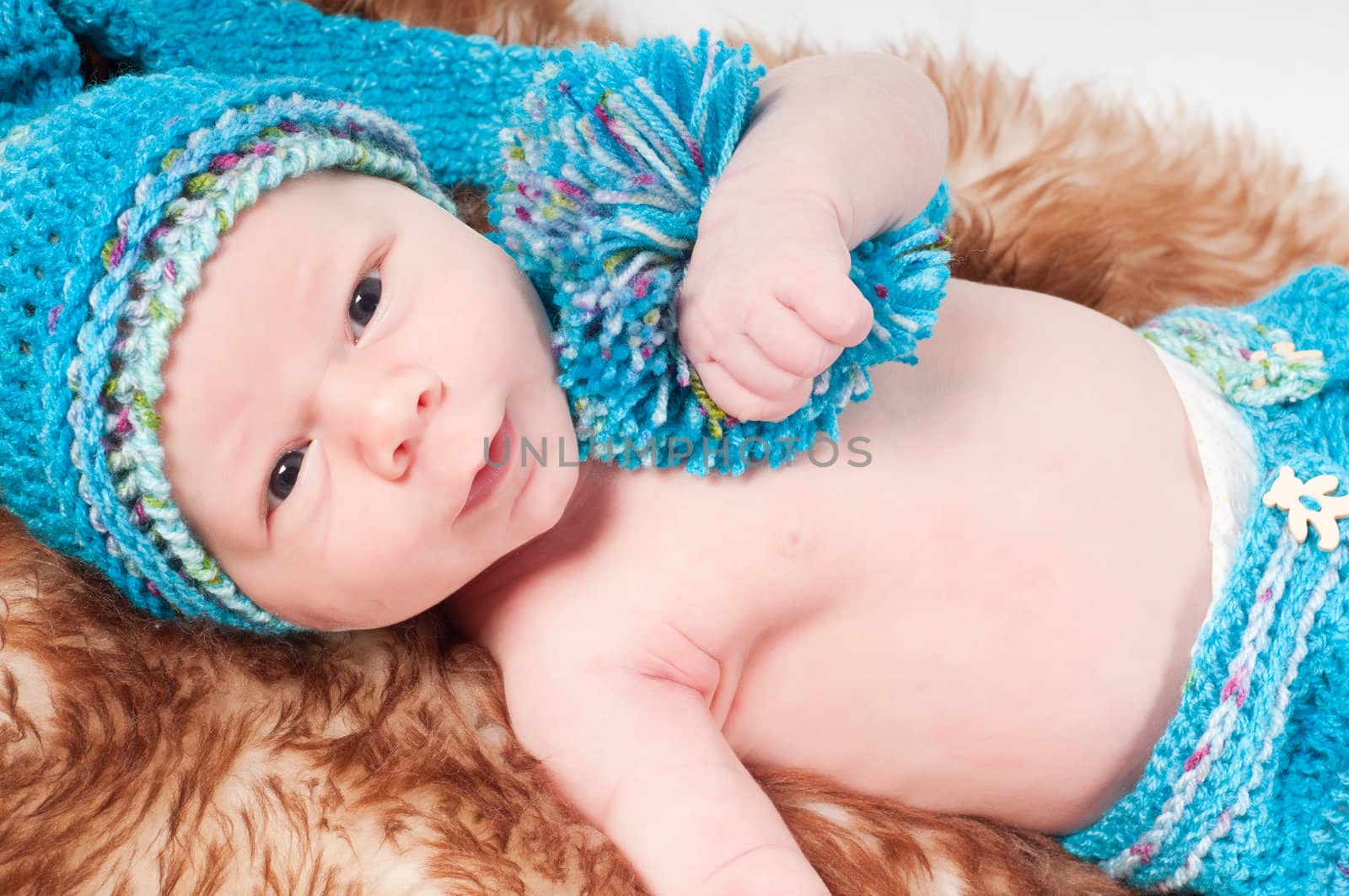 Newborn baby in long blue knitted hat with pom-pon