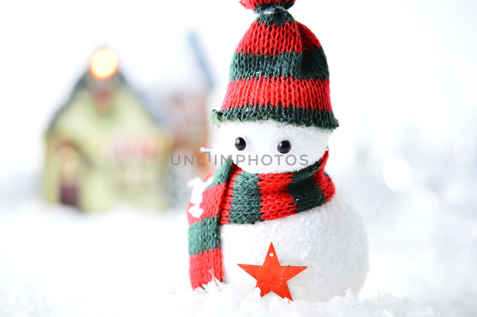 snowman with black and red hat and scarf in artificial snow on white background