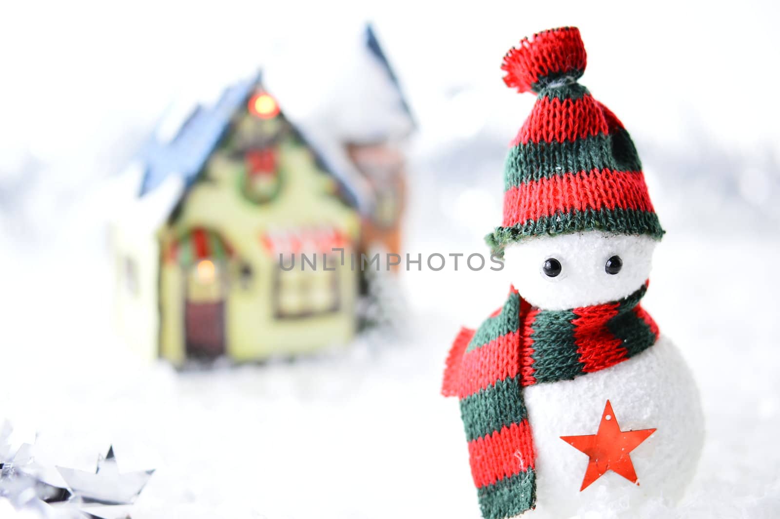 snowman with black and red hat and scarf in artificial snow on white background