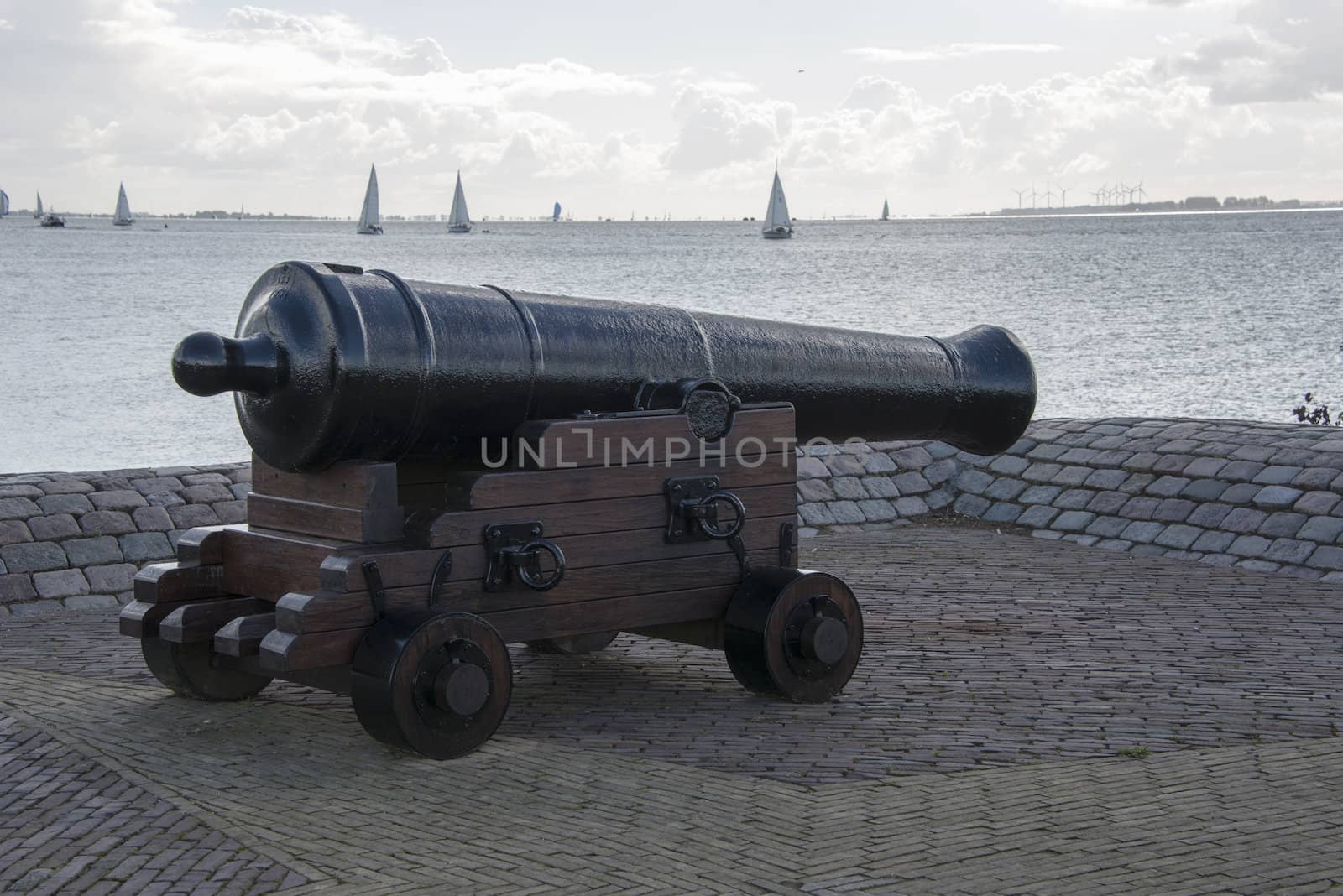cannon in the harbor with boats on the background