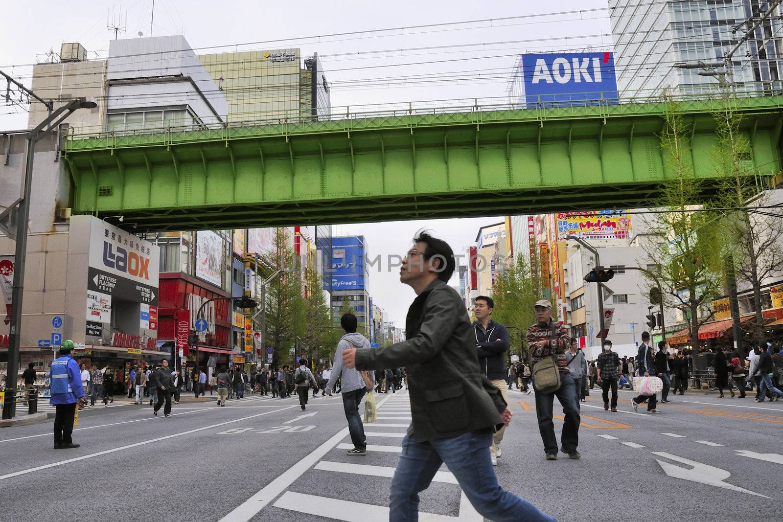 TOKYO, JAPAN -APRIL 17, 2011 : man crosses over street in Tokyo Alihabara area. Akihabara district is very crowded and closed for car traffic every Sunday, so pedestrians walks freely inside biggest and worldwide famous electronics market area.  