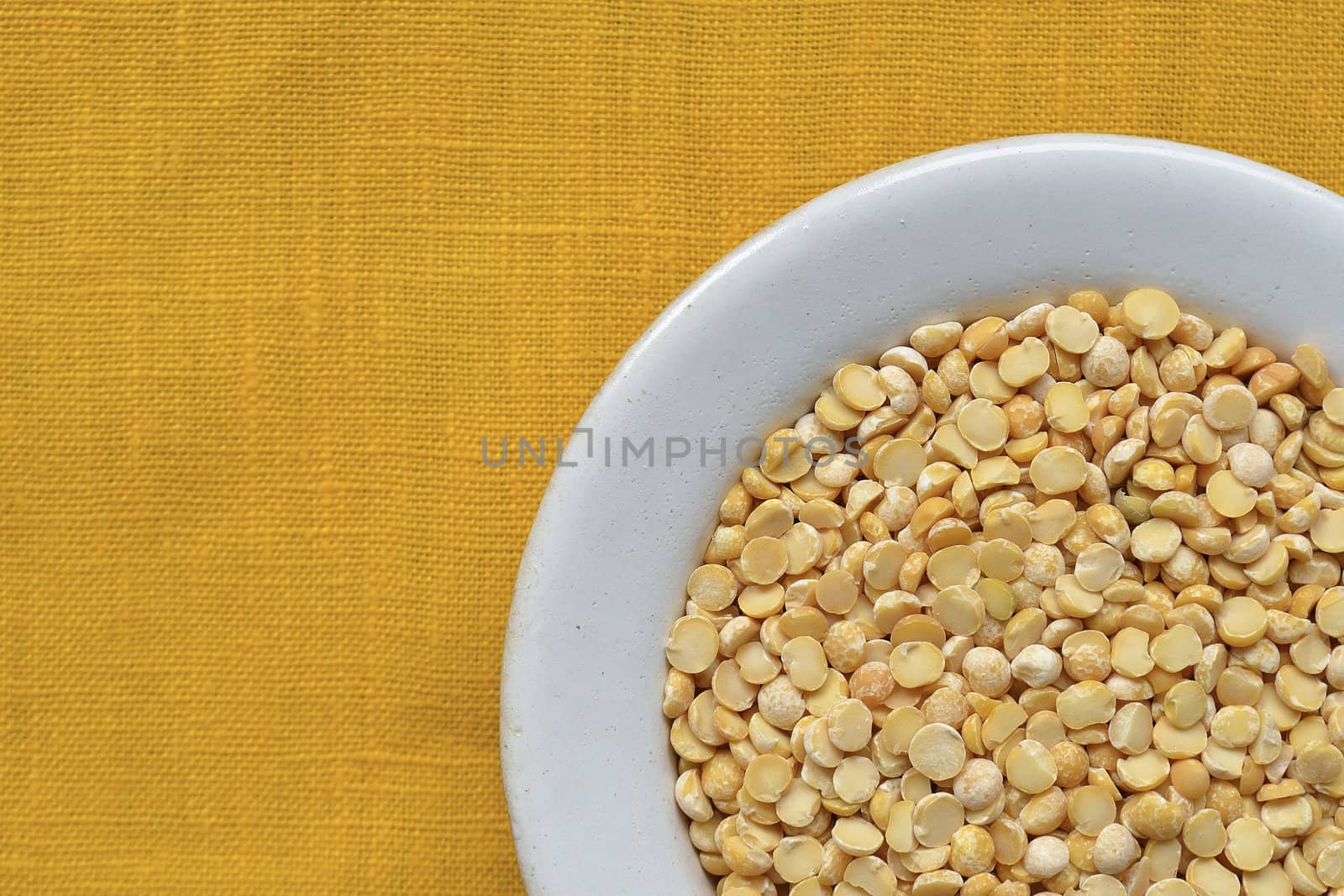 many dry peas beans in white bowl over yellow tablecloth background