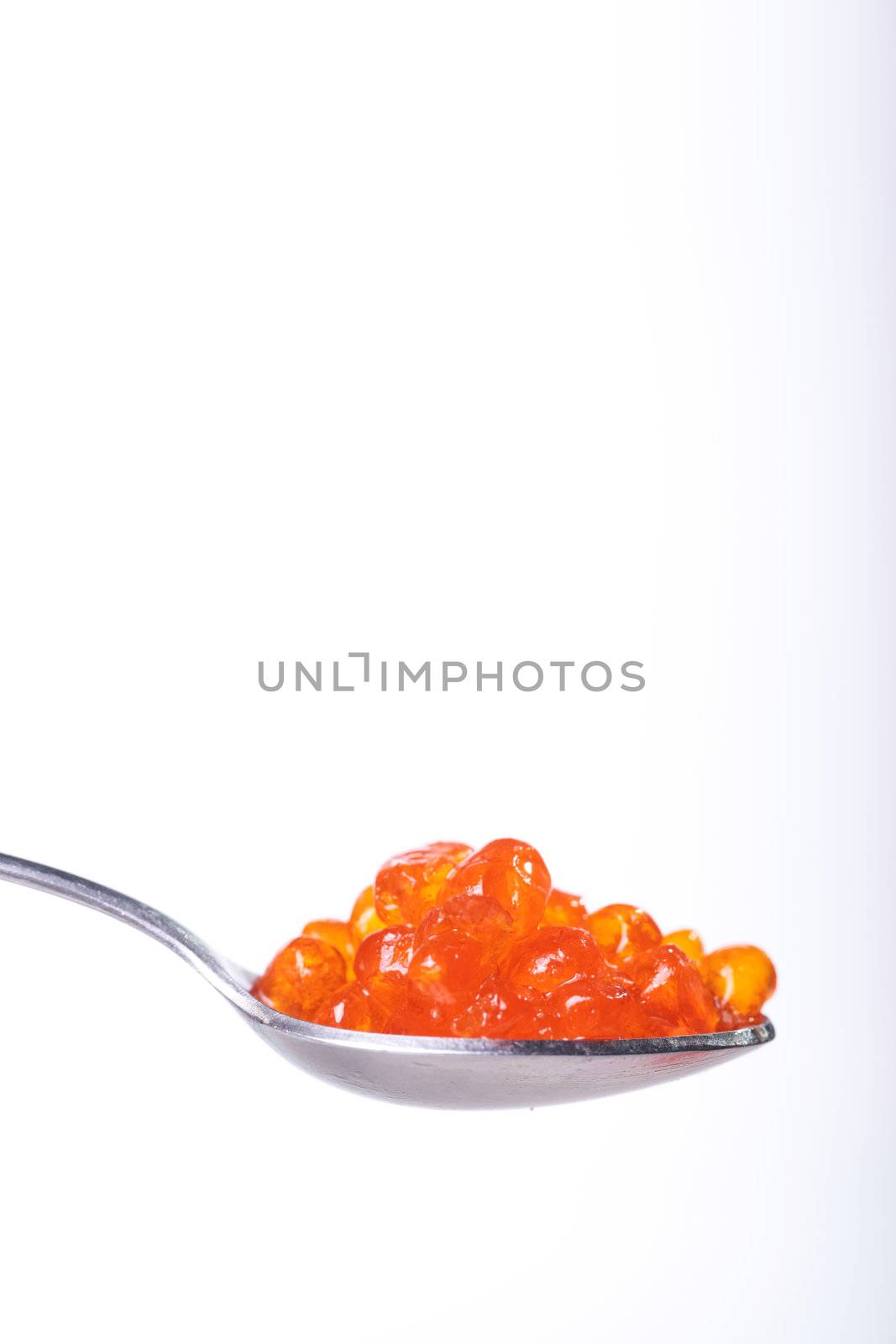 Close up of red tasty caviar in a spoon over a white background