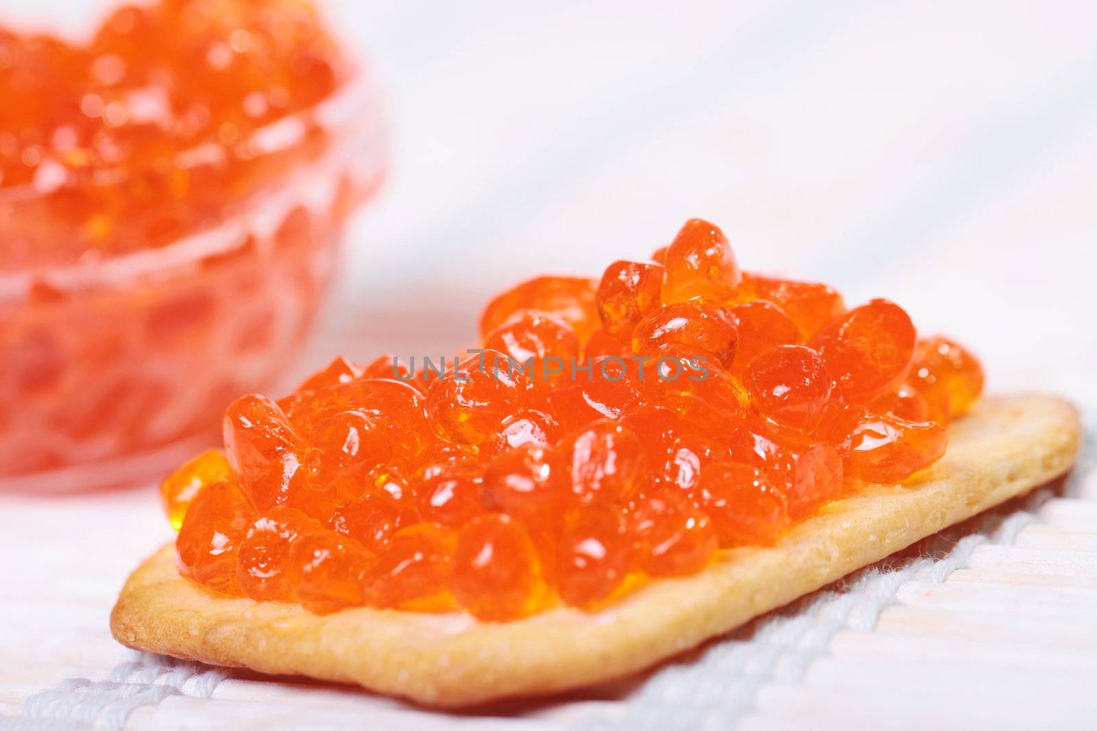 Close up of red tasty caviar in a glass jar with cracker