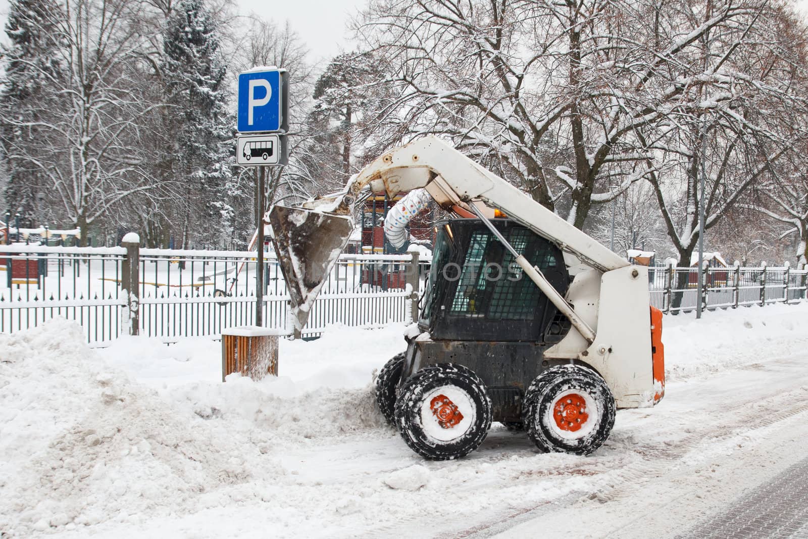 small excavator bobcat working on the street, cleaning snow