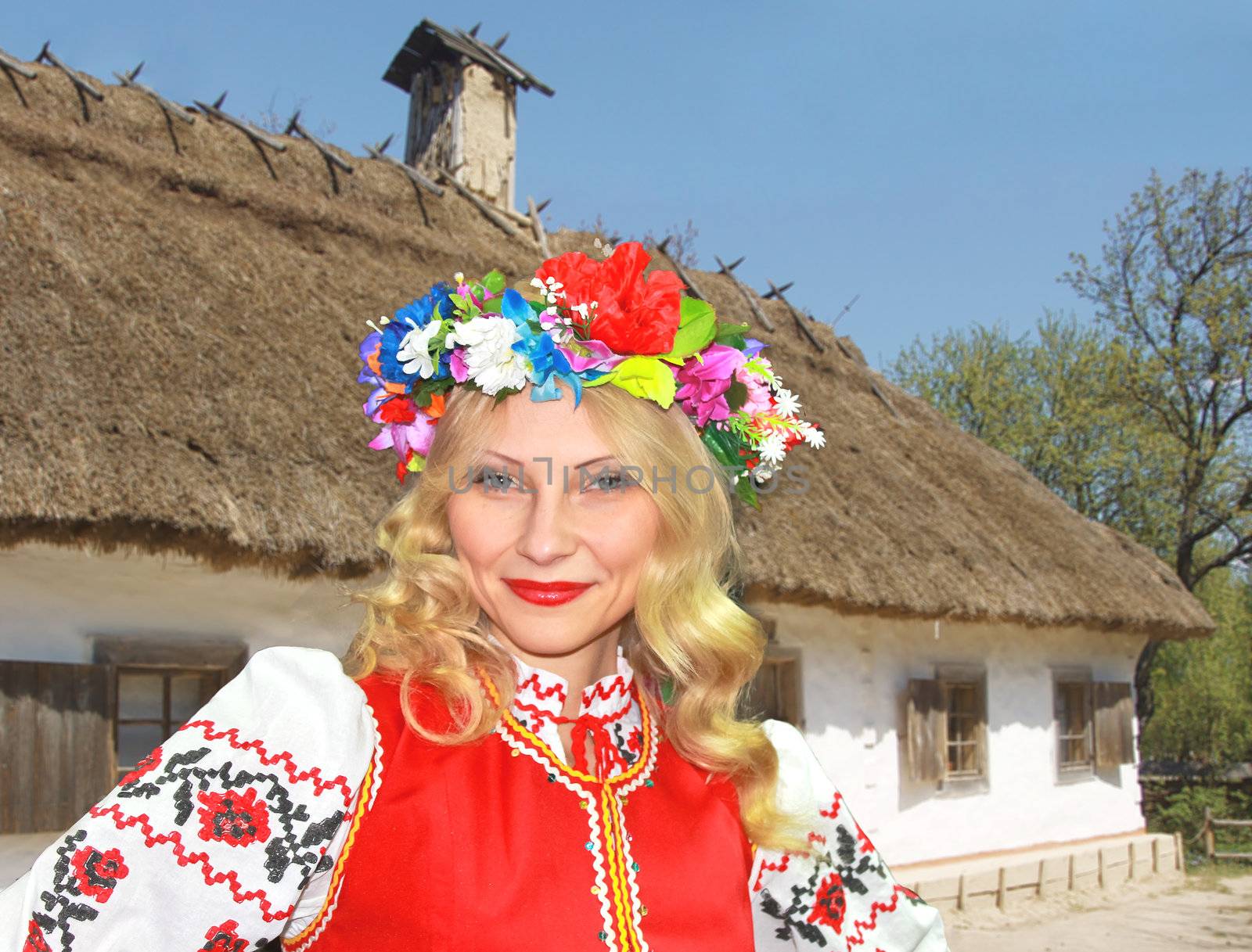 Beautiful Ukrainian girl in national clothes near the rural house