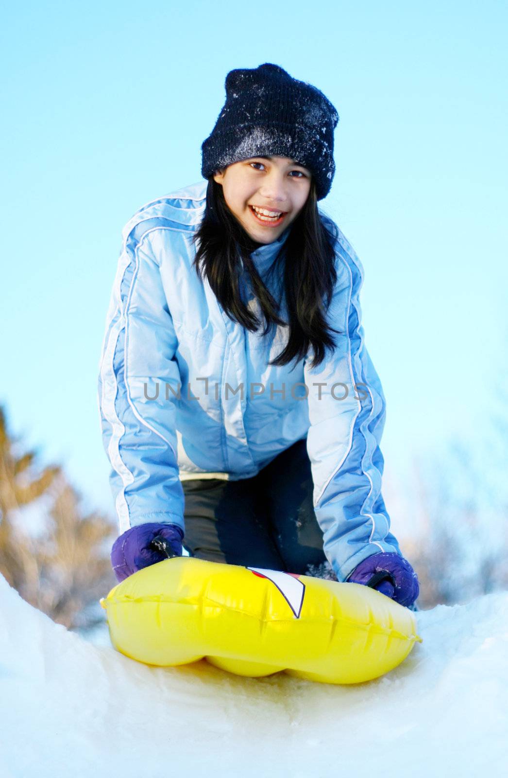 Biracial teen girl sledding down snow hill by jarenwicklund