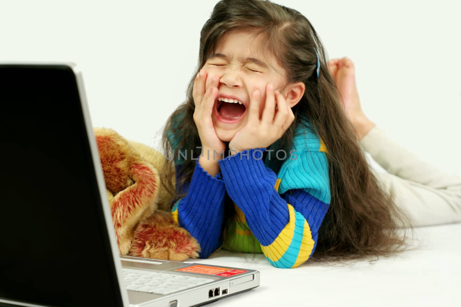 Little girl playing on her laptop on floor
