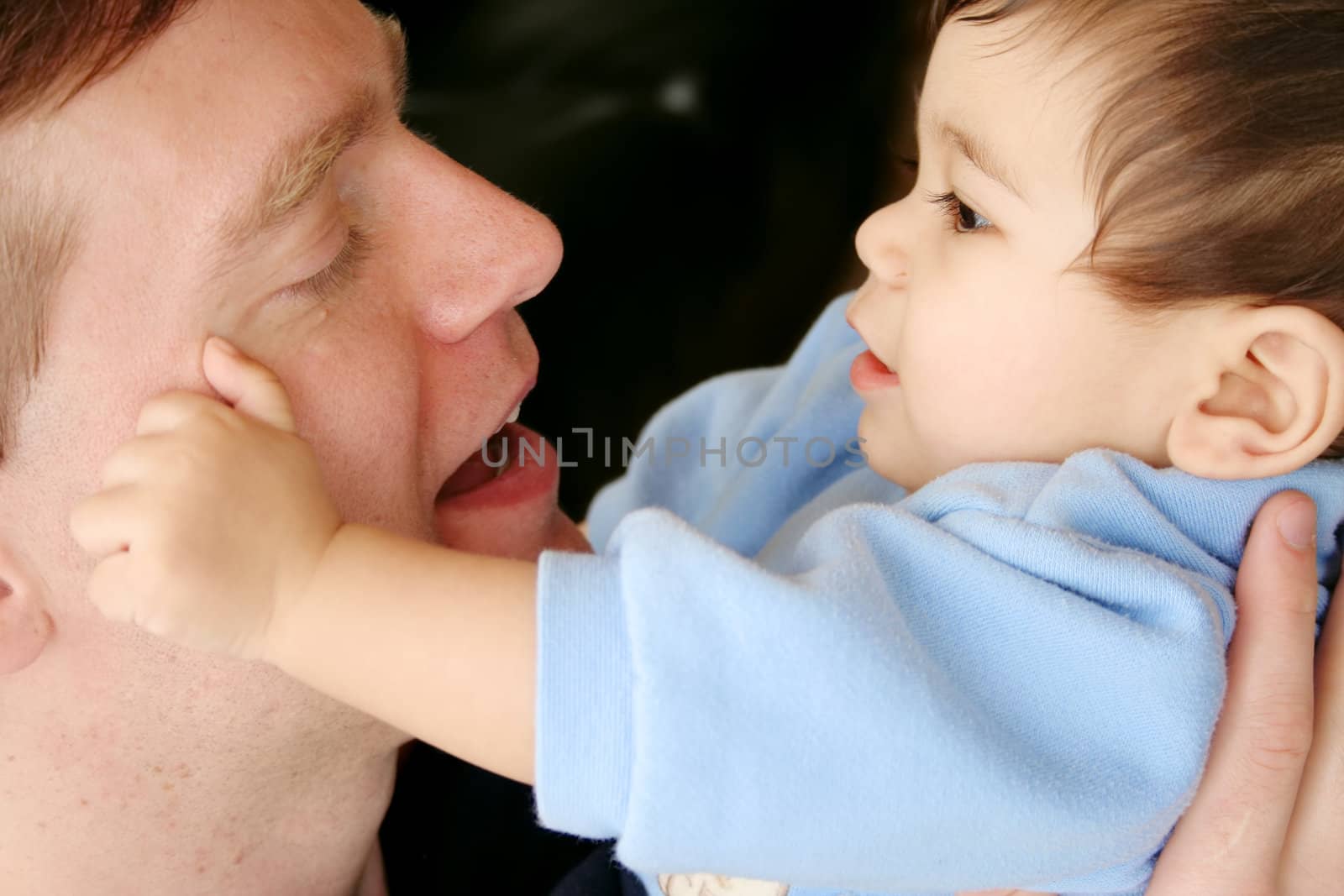 Baby tenderly touching dad's face