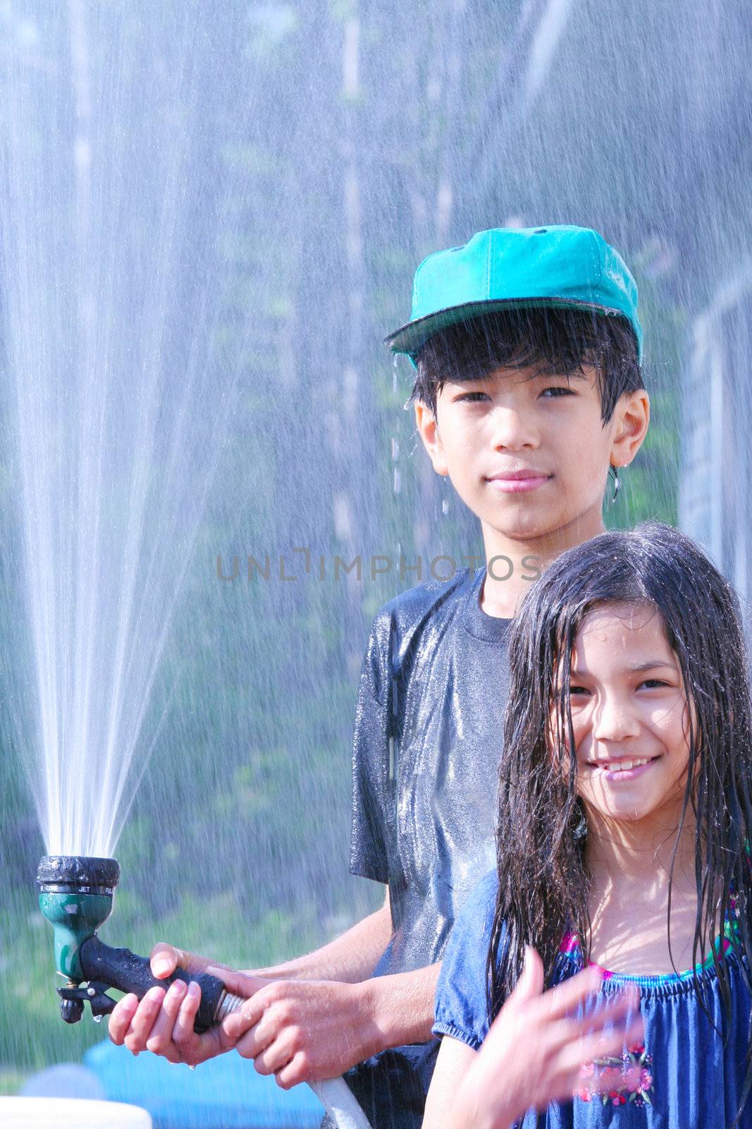 Brother and sister playing with water hose