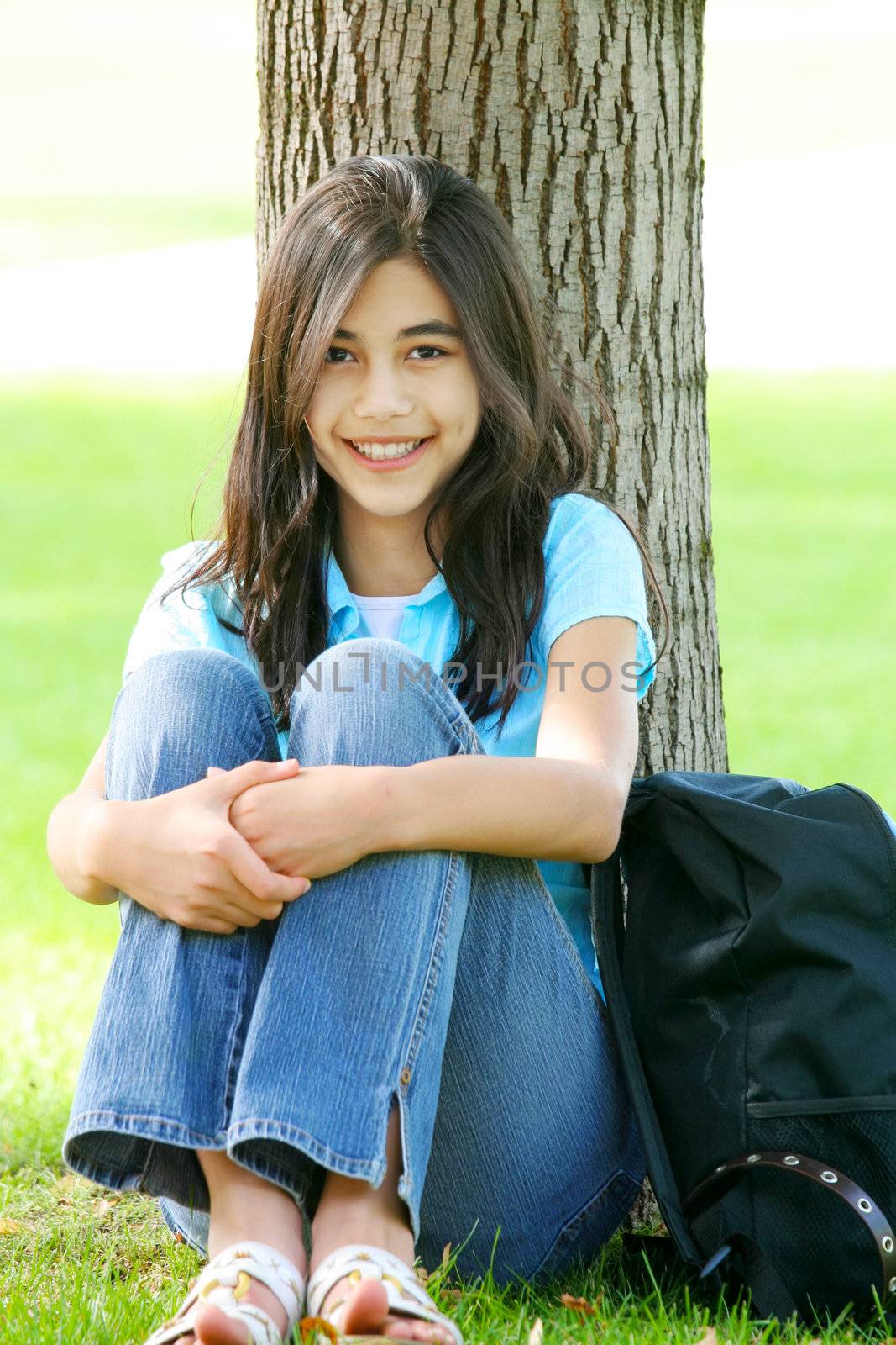 Young teen girl sitting against tree by jarenwicklund