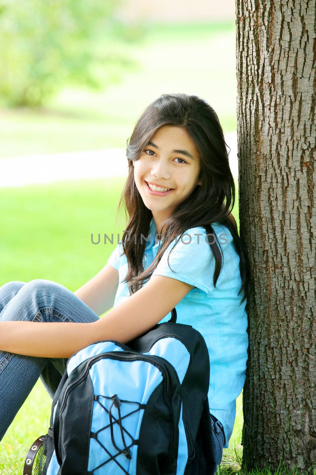 Teen girl sitting with backpack against tree by jarenwicklund