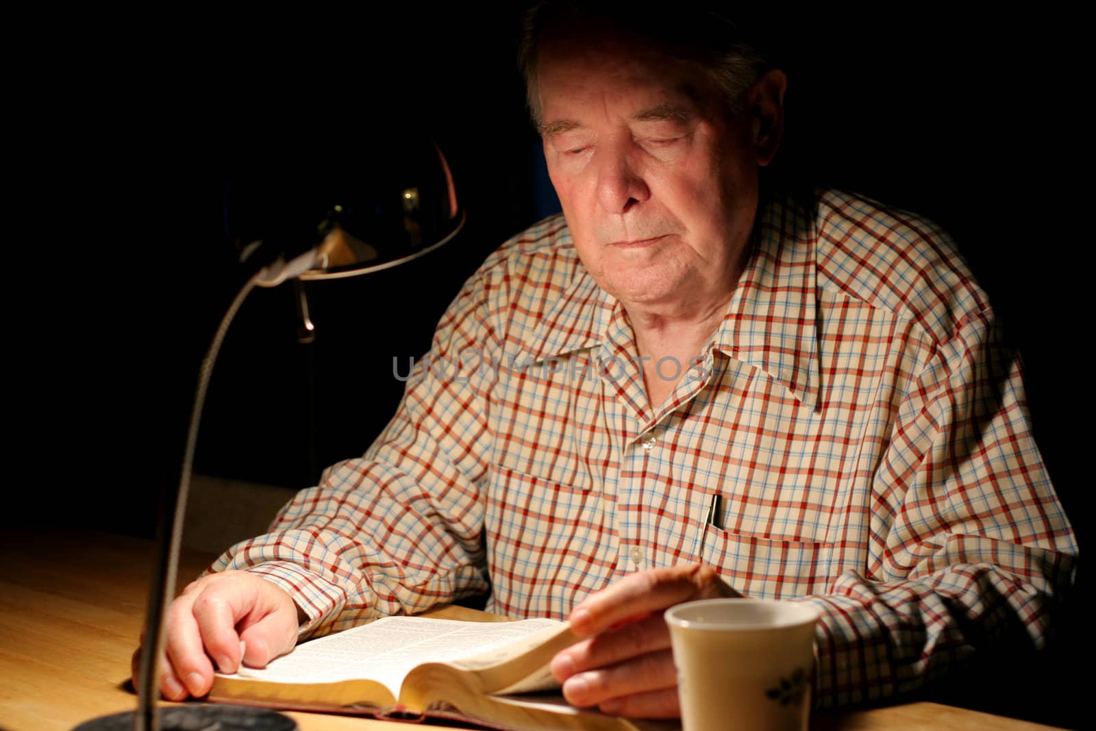 ELderly man reading Bible  at night by jarenwicklund