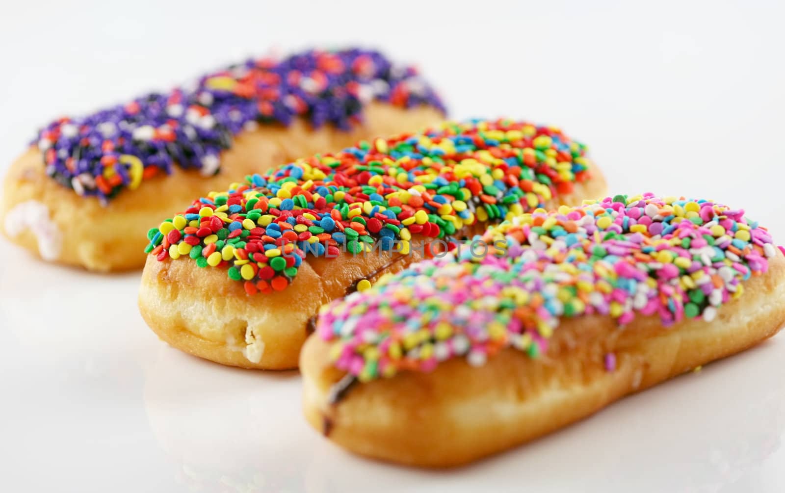 Three colorful donuts topped with sprinkles by jarenwicklund