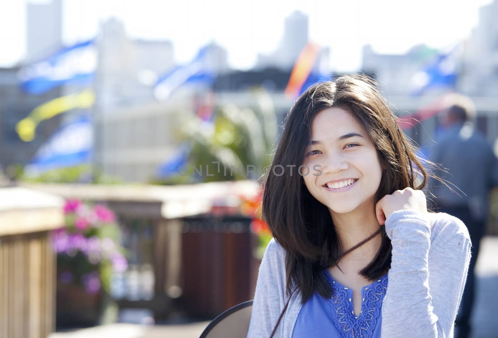 Young biracial teen girl smiling outdoors, sunny colorful background colors