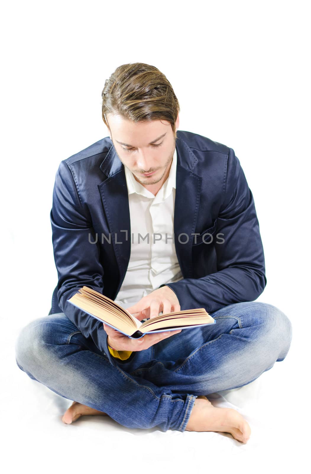 Handsome young man reading or studying on floor by artofphoto