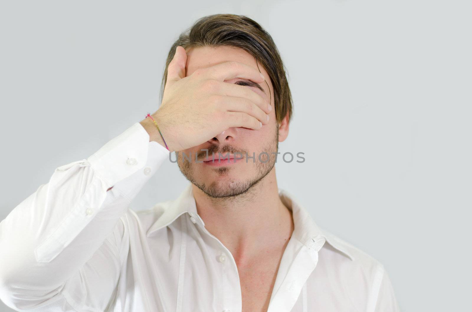 Handsome young man covering eyes with his hand by artofphoto