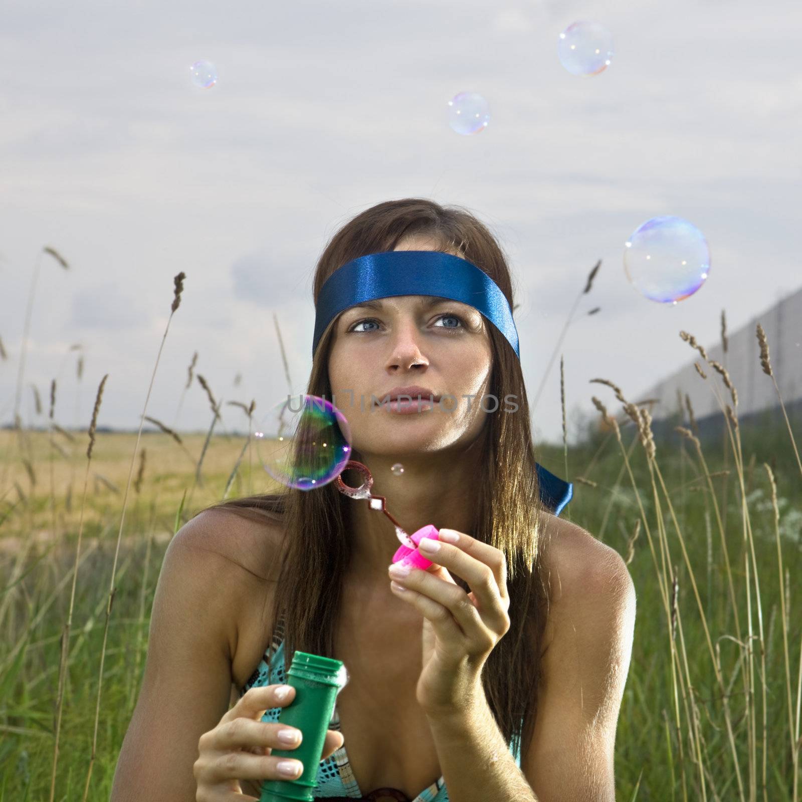 thoughtful woman blowing soap bubbles by ssuaphoto