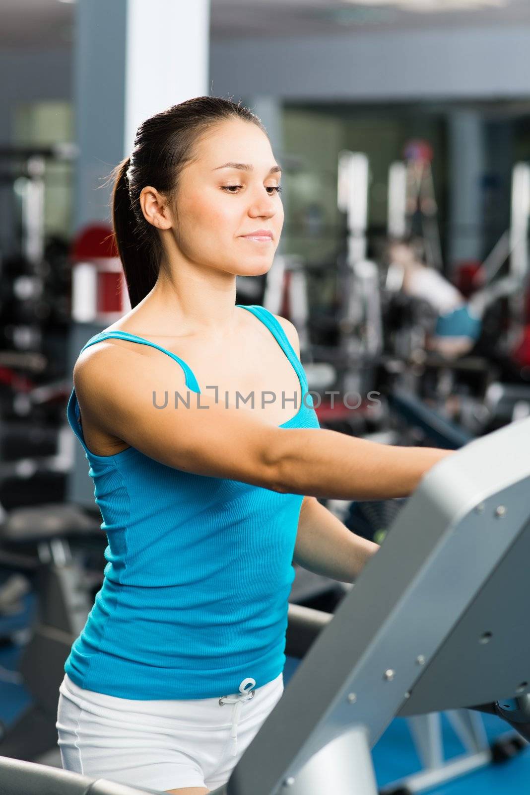 attractive young woman adjusts the treadmill at the beginning of training, do fitness in the sport club