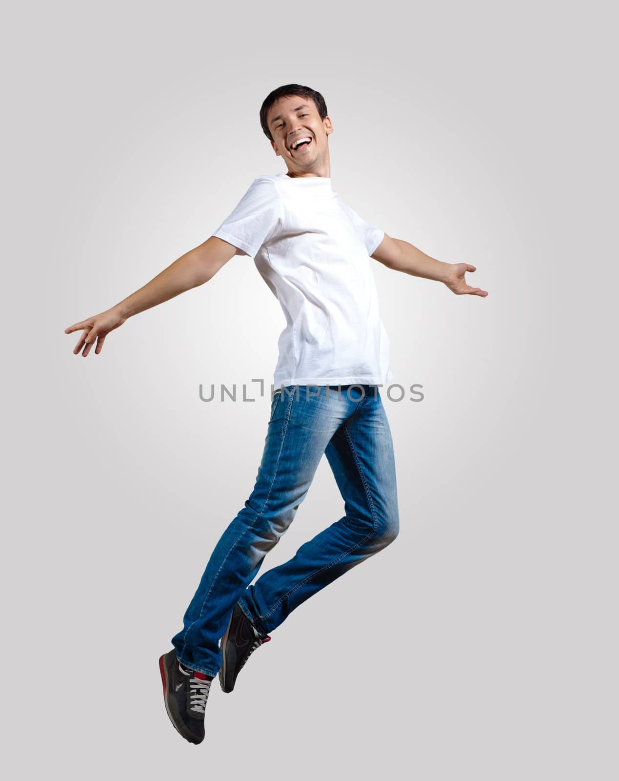 Modern slim hip-hop style man jumping dancing on a grey background