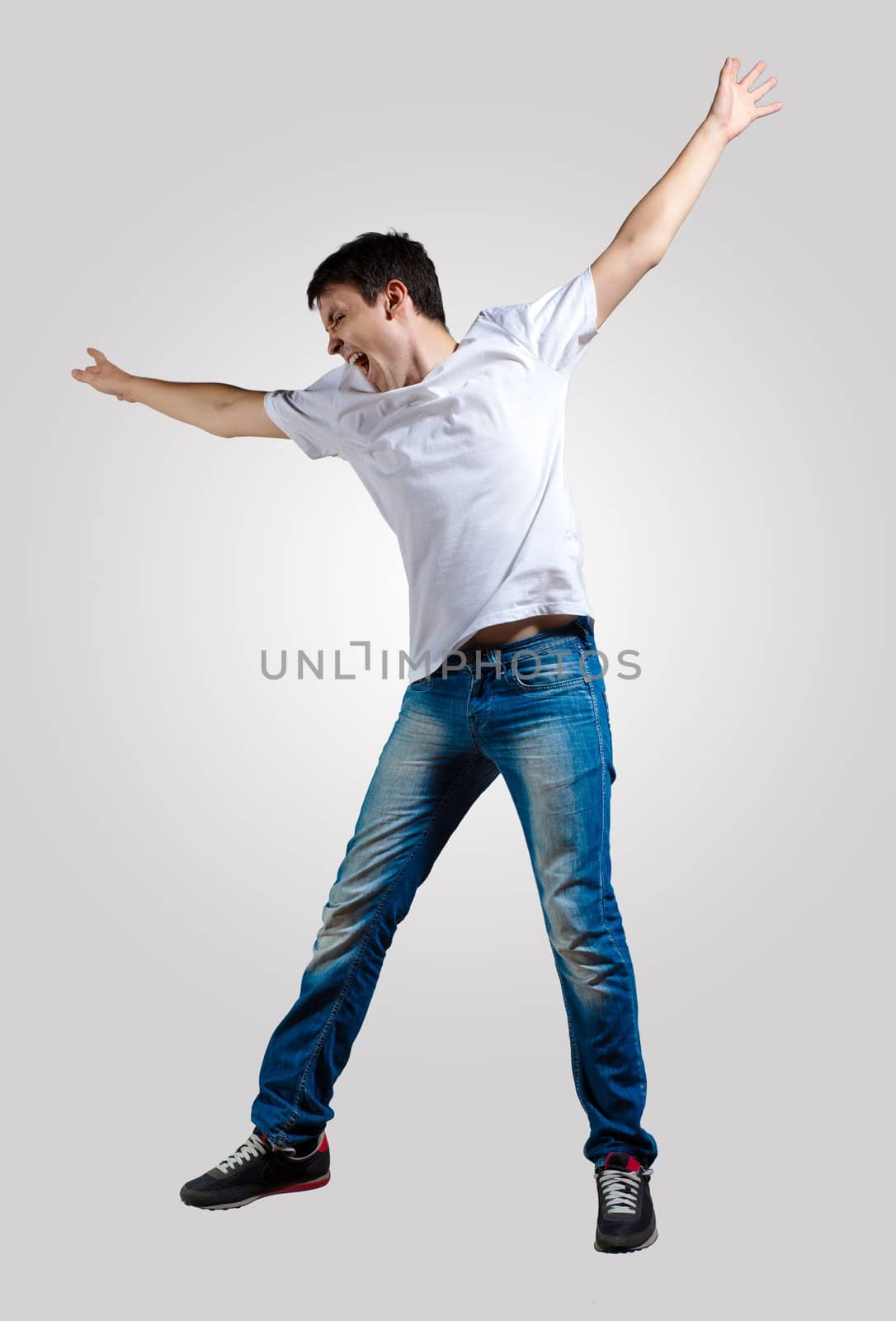 Modern slim hip-hop style man jumping dancing on a grey background