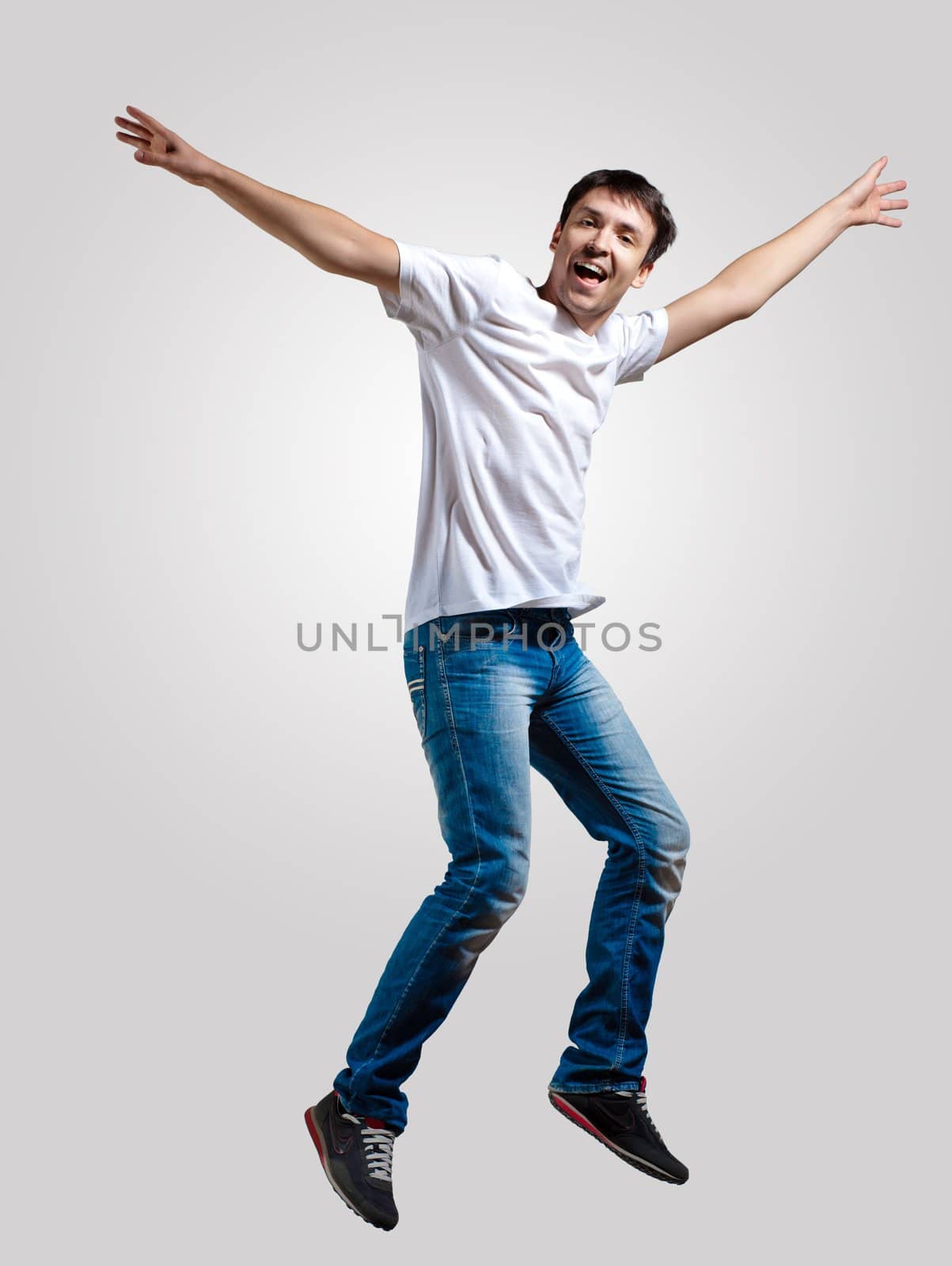 Modern slim hip-hop style man jumping dancing on a grey background