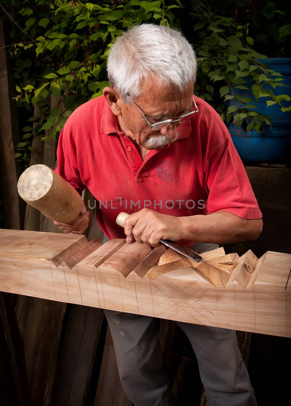 Old woodcarver working with mallet and chisel 9