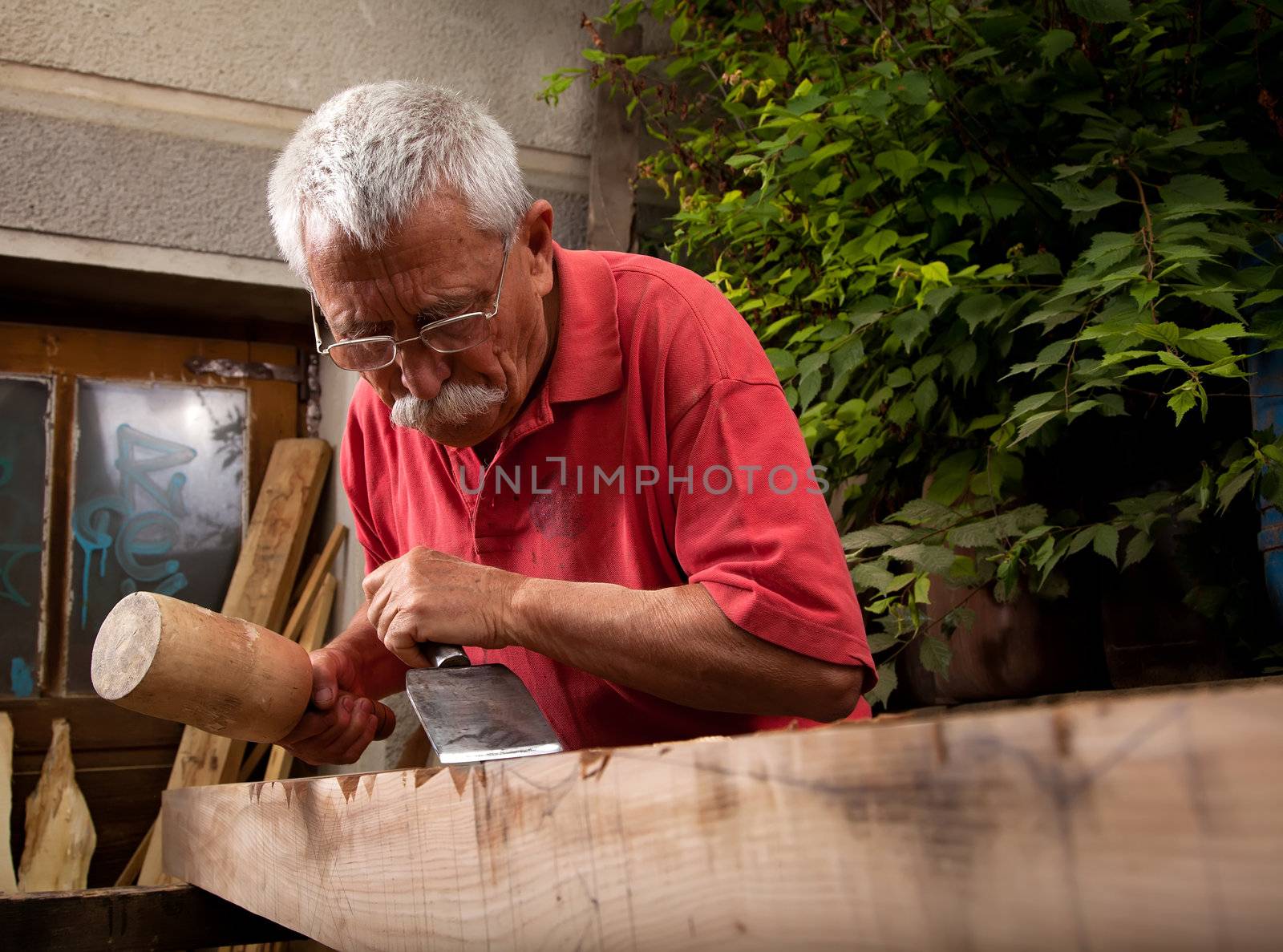 Old woodcarver working with mallet and chisel 6