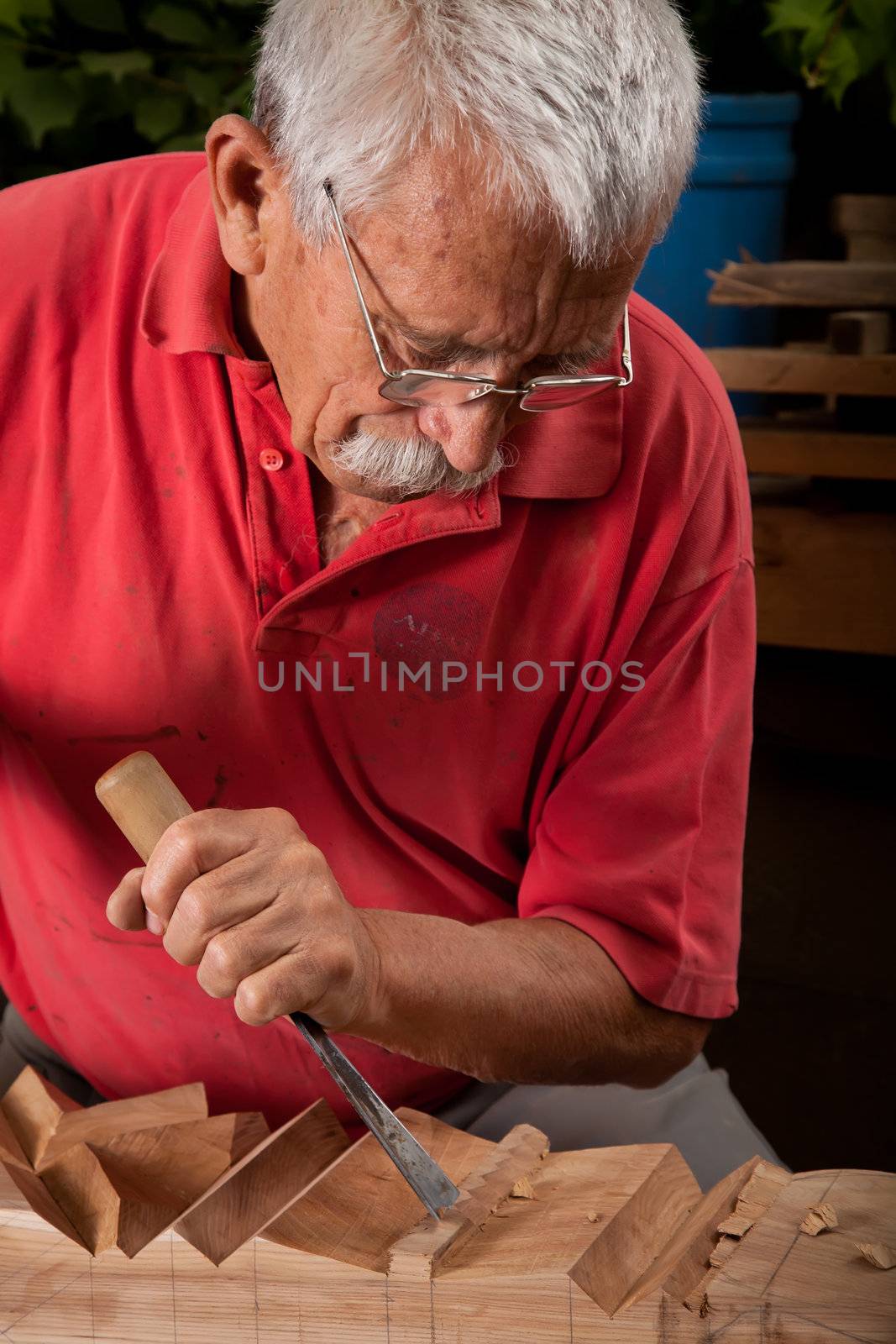 Old woodcarver working with mallet and chisel