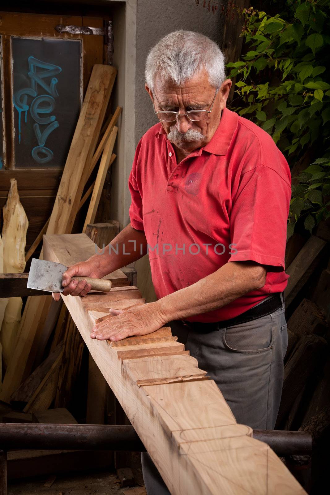 Old woodcarver working with mallet and chisel