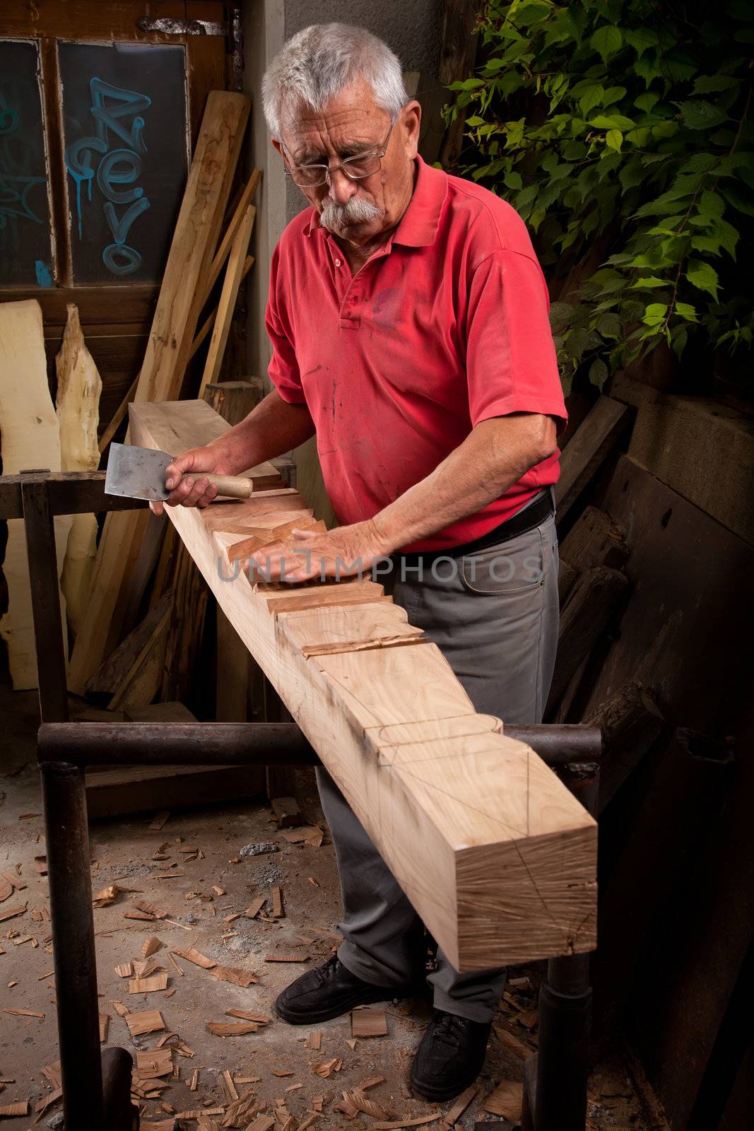 Old woodcarver working with mallet and chisel